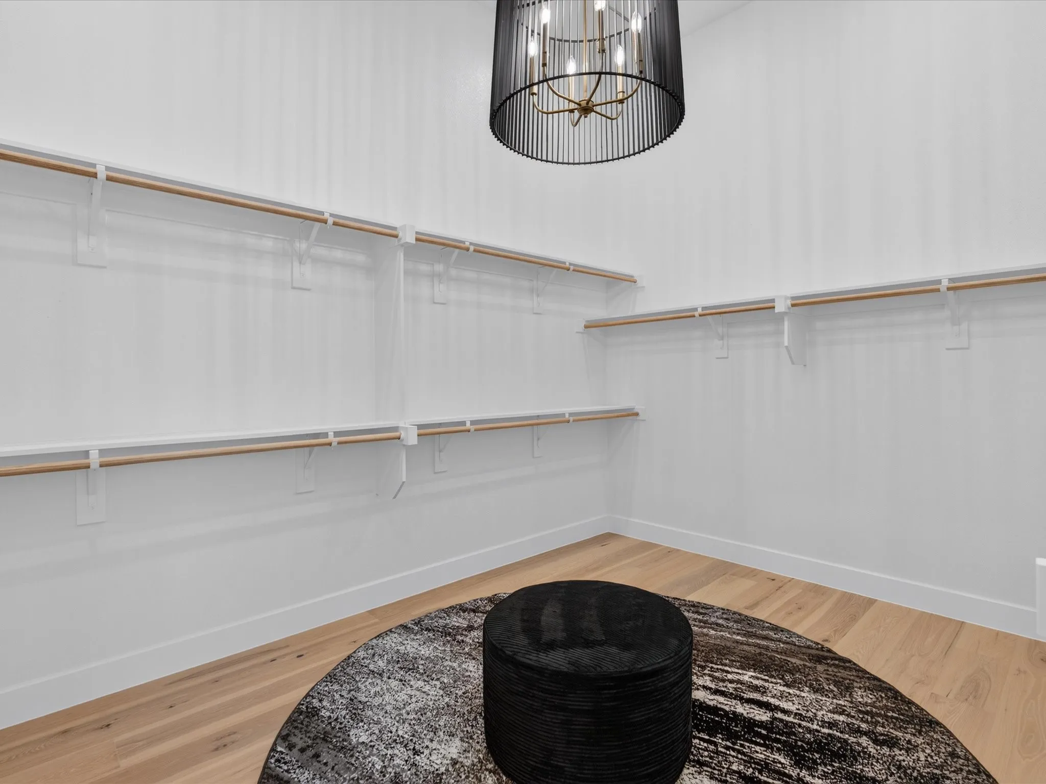 Spacious walk-in closet featuring multiple shelving units, light wood-finish flooring, and a contemporary chandelier