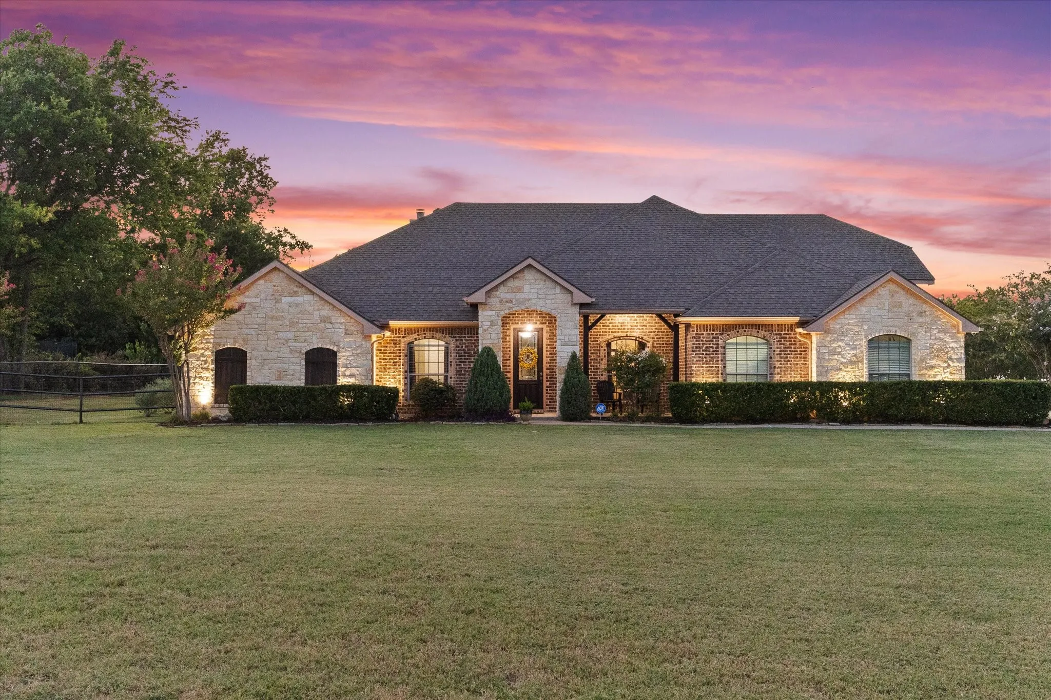 Stone and brick exterior with a dark shingle roof, featuring arched windows and covered entryway