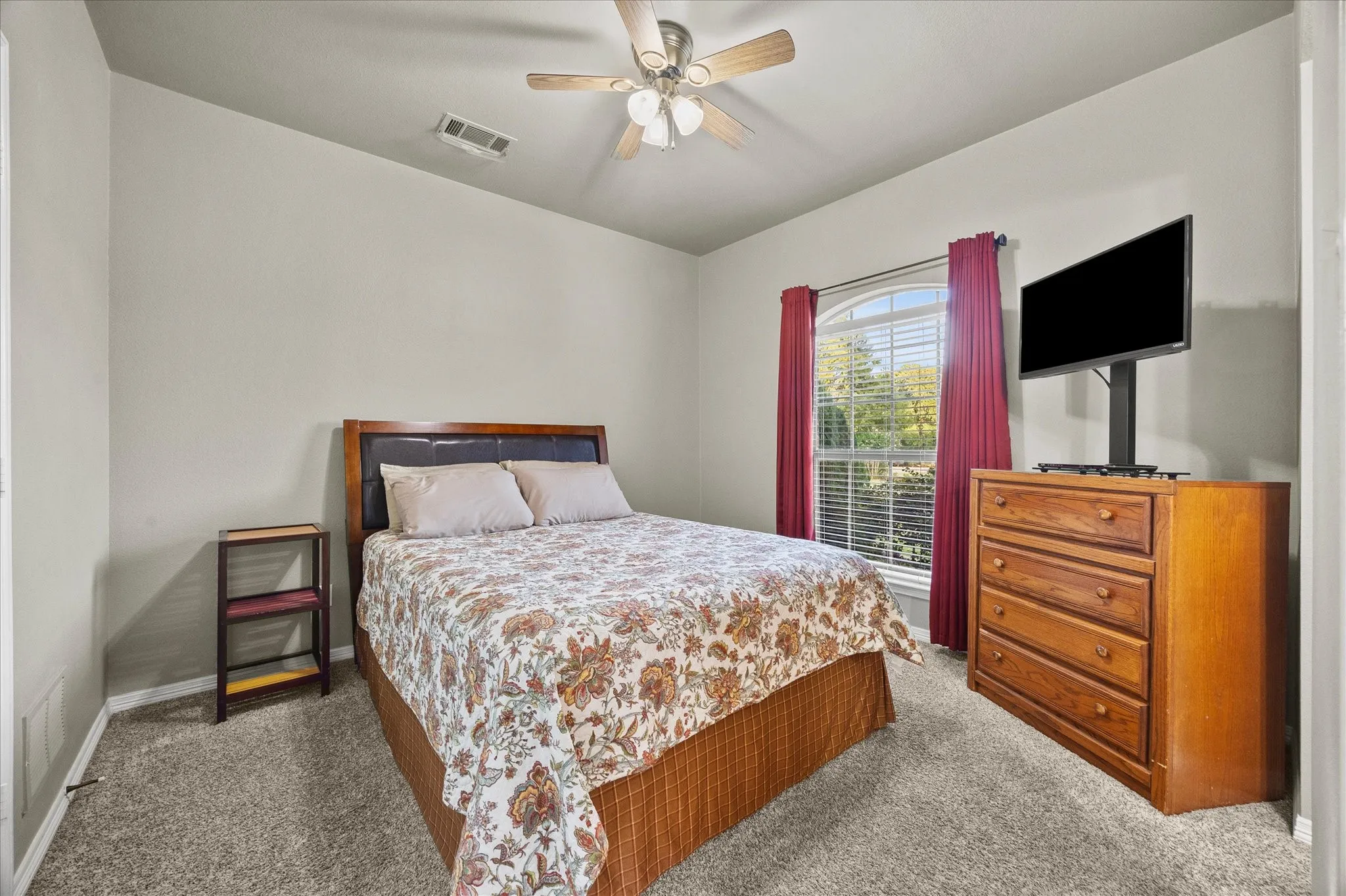 Arched window with blinds, ceiling fan, and carpeted flooring