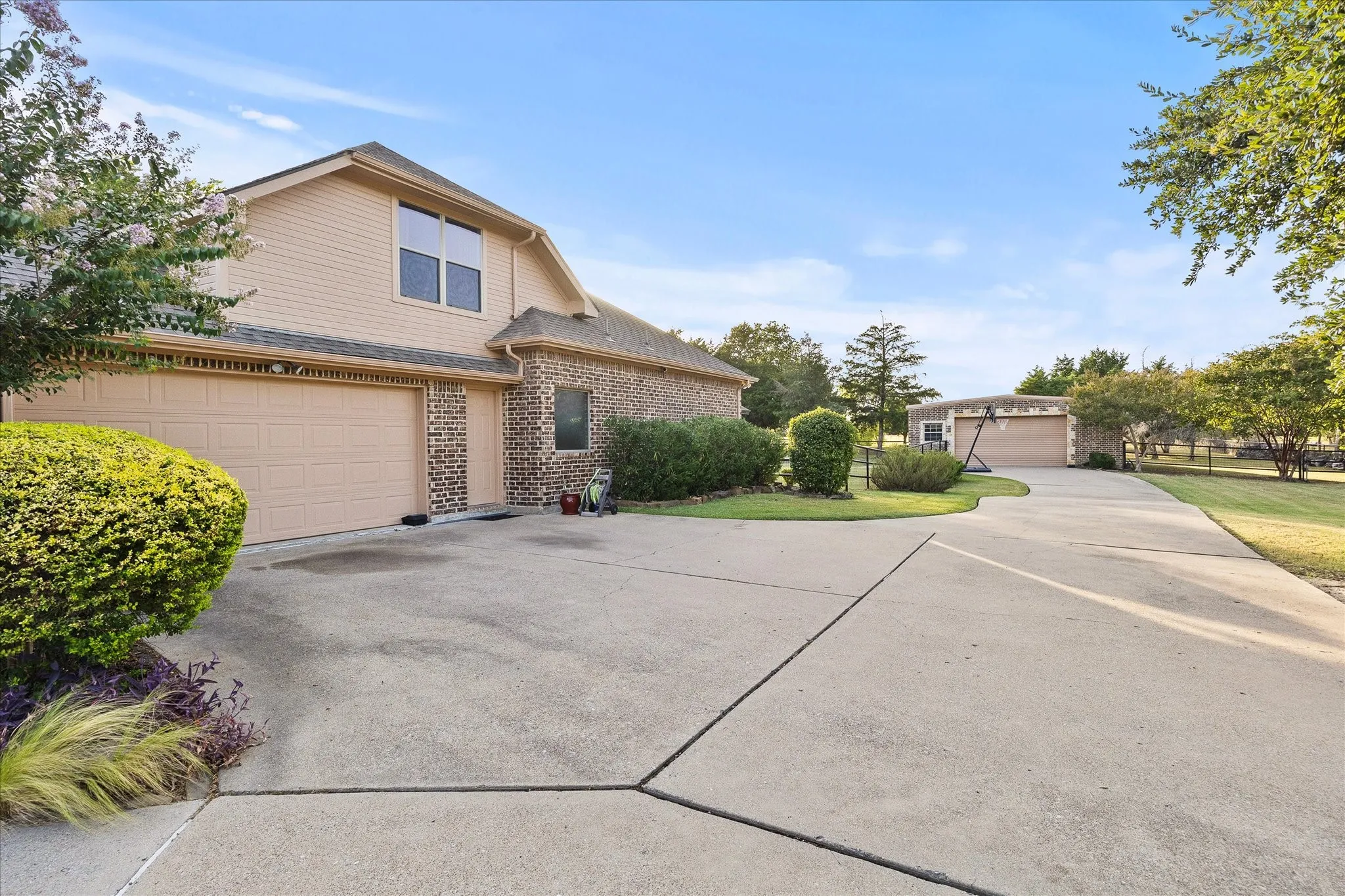 Two-story brick and siding exterior with an attached two-car garage, concrete driveway, and a detached structure with an additional garage