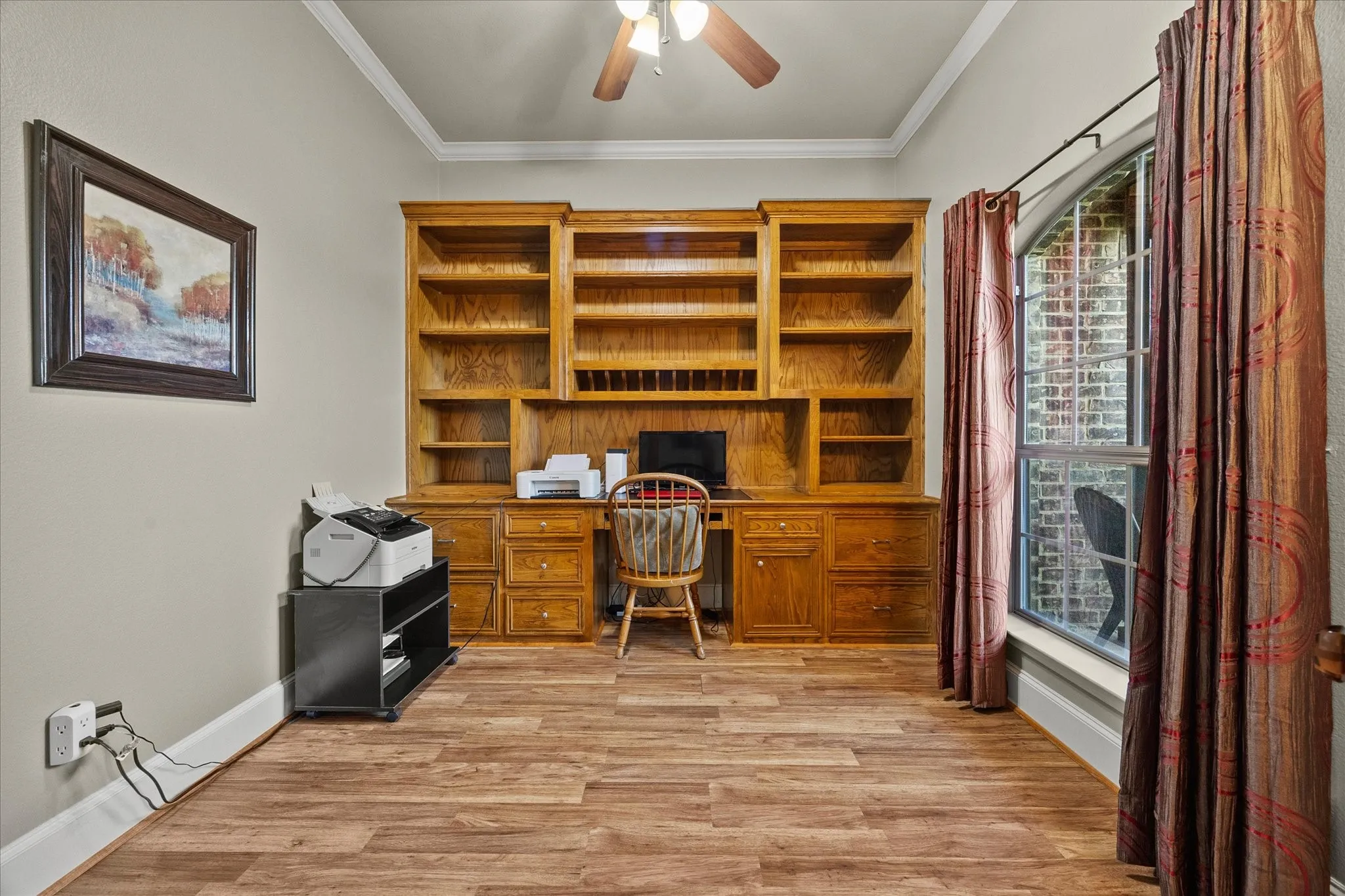 Built-in wood cabinetry with shelving, wood-finish flooring, and arched window with exterior brick detail