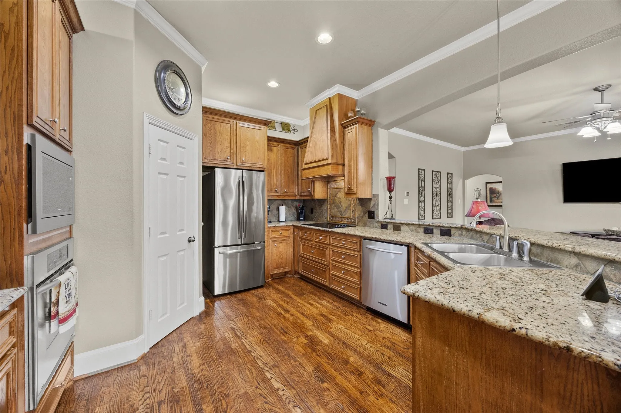 Kitchen featuring wood-finish flooring, light-colored countertops, stainless steel appliances, and wood cabinetry
