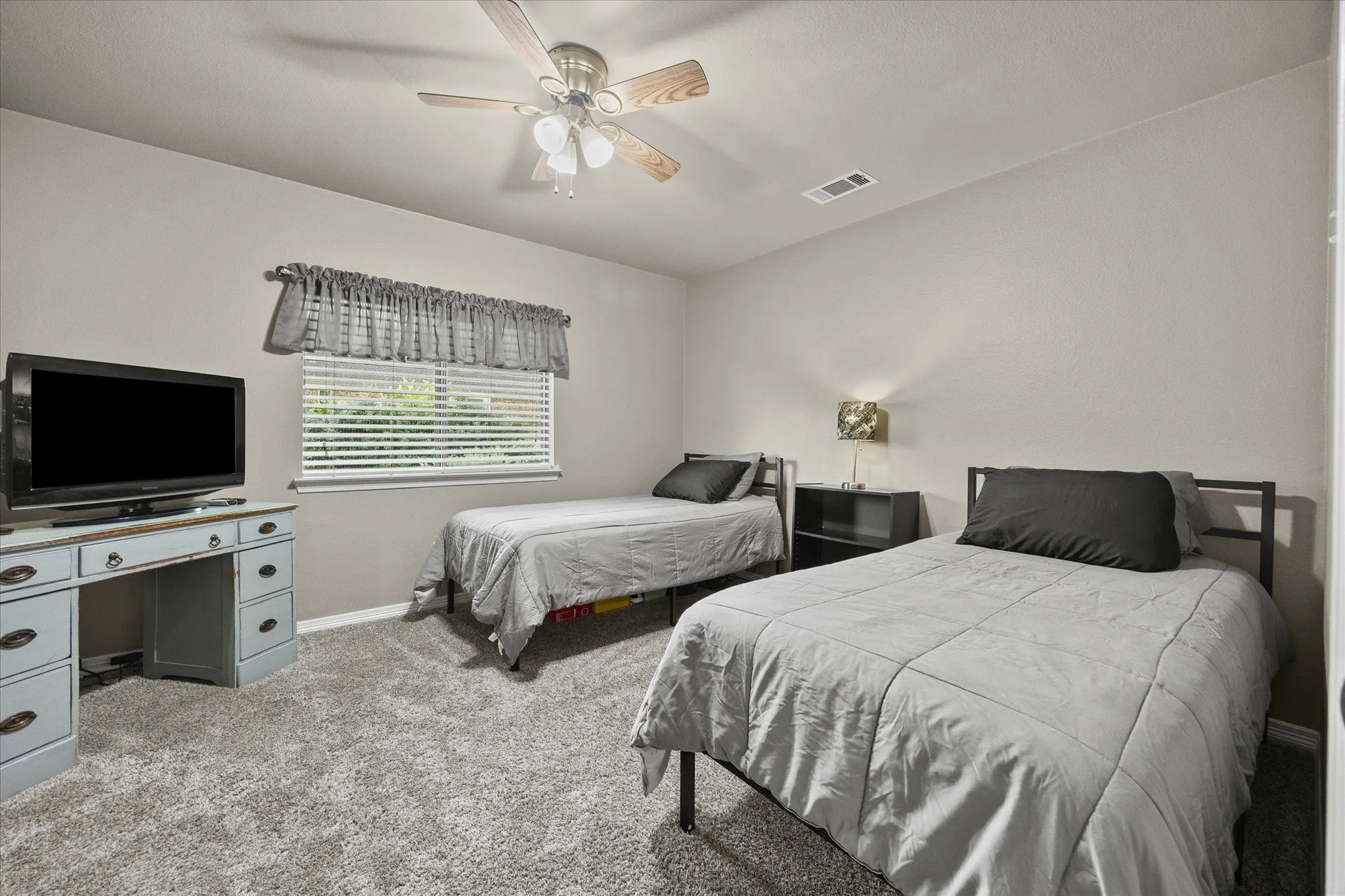 Carpeted room with a ceiling fan, a window with horizontal blinds, and neutral-toned walls
