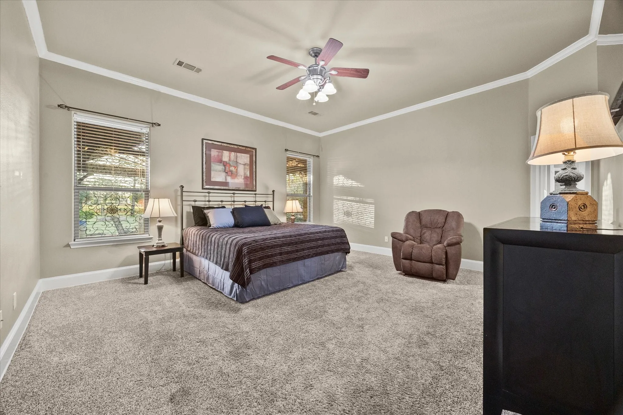 Spacious room featuring carpeting, crown molding, a ceiling fan, and multiple windows