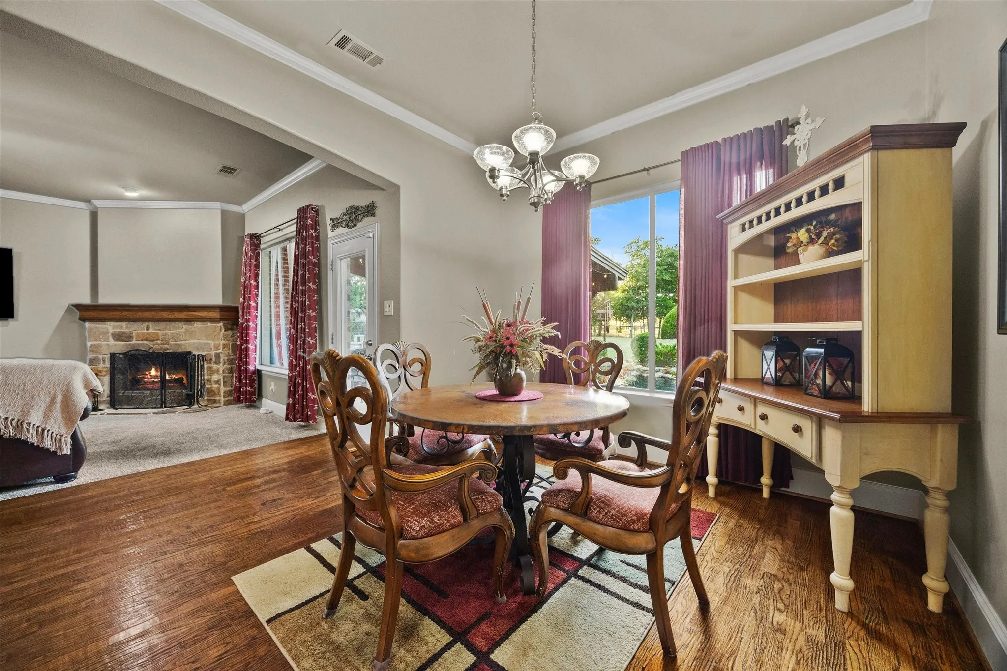 Hardwood flooring, recessed lighting, crown molding, stone fireplace, and a built-in display cabinet