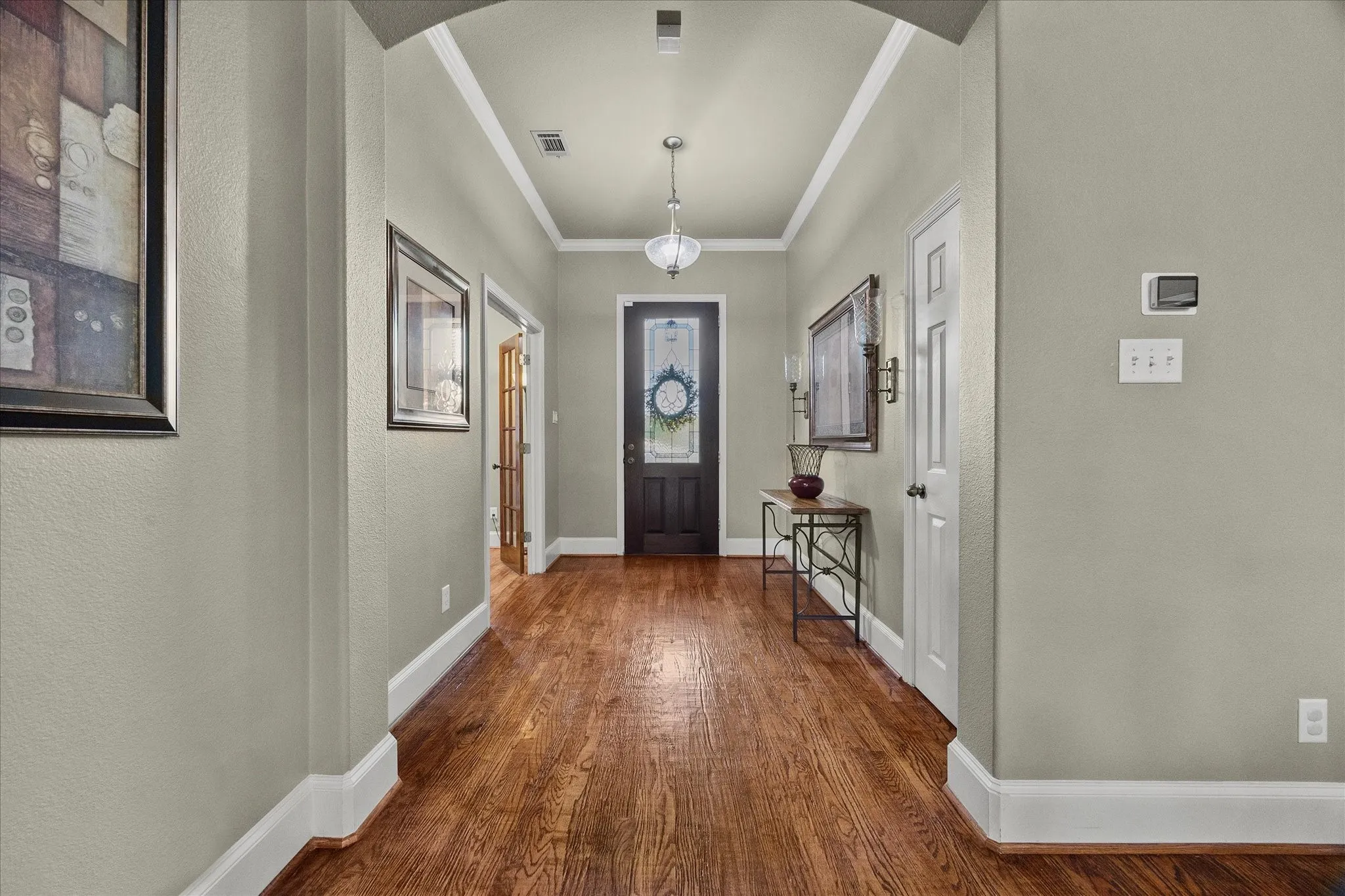 Wood-finish flooring throughout, complemented by a suspended light fixture and an arched entryway
