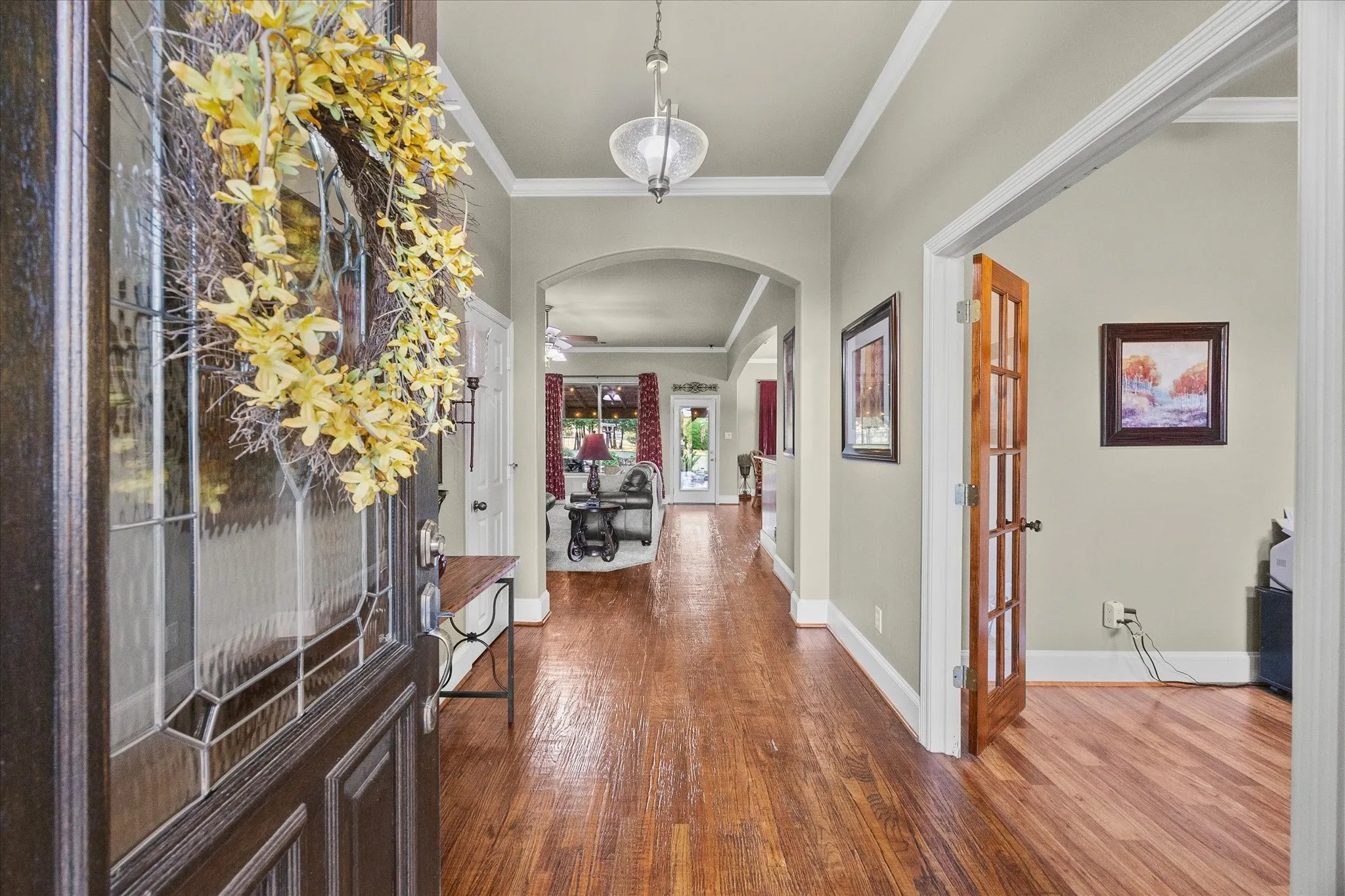 Decorative glass-paneled entry door, wood-finish flooring, arched doorways, crown molding, and recessed lighting