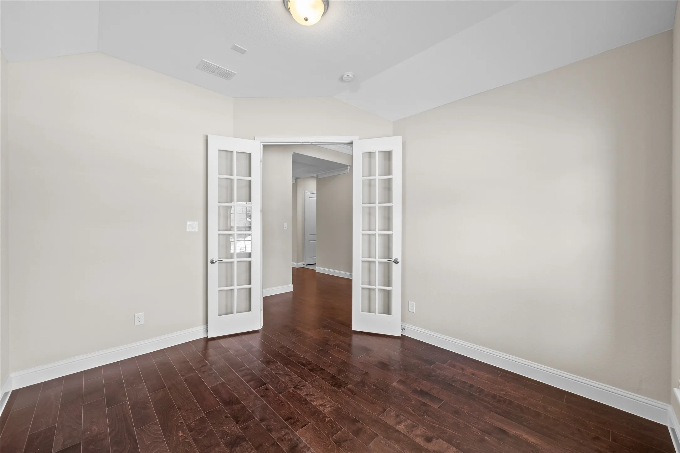 Room with dark wood-finish flooring, light neutral walls, and a vaulted ceiling