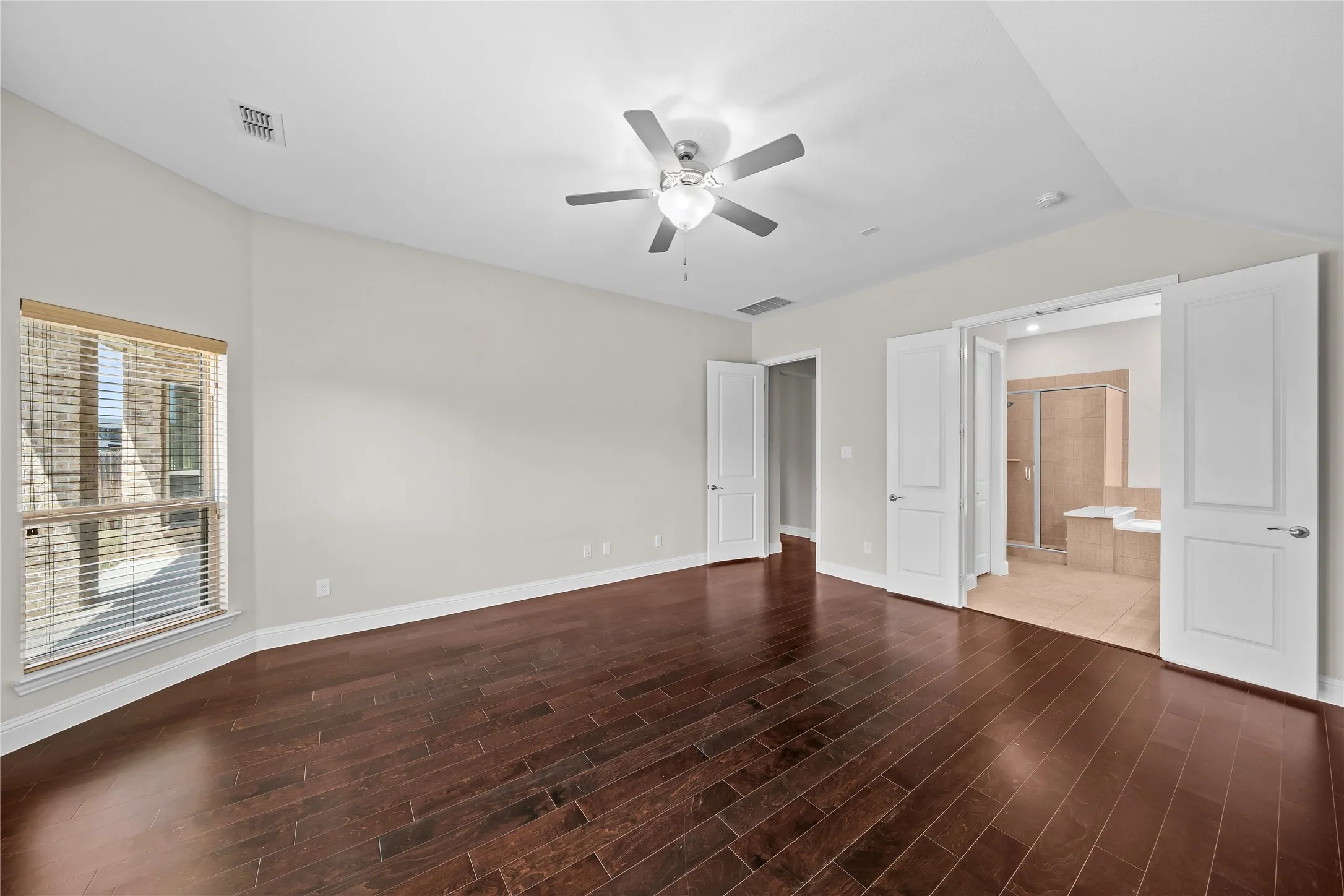 Rich wood-finish flooring, a tray ceiling, and a ceiling fan with integrated lighting