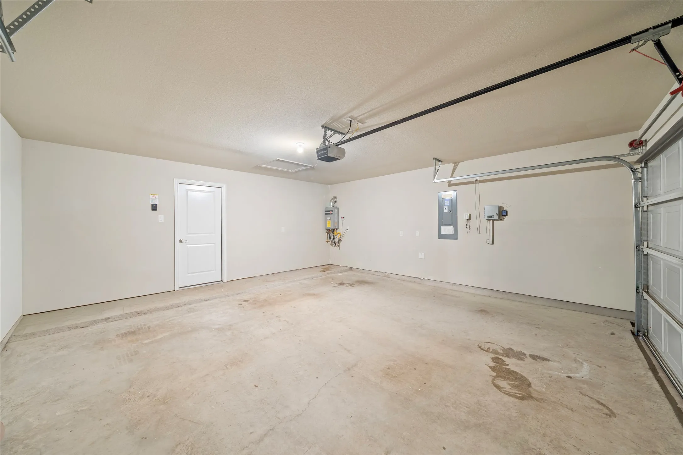 Concrete flooring, interior access door, wall-mounted utility panel, and garage door mechanism