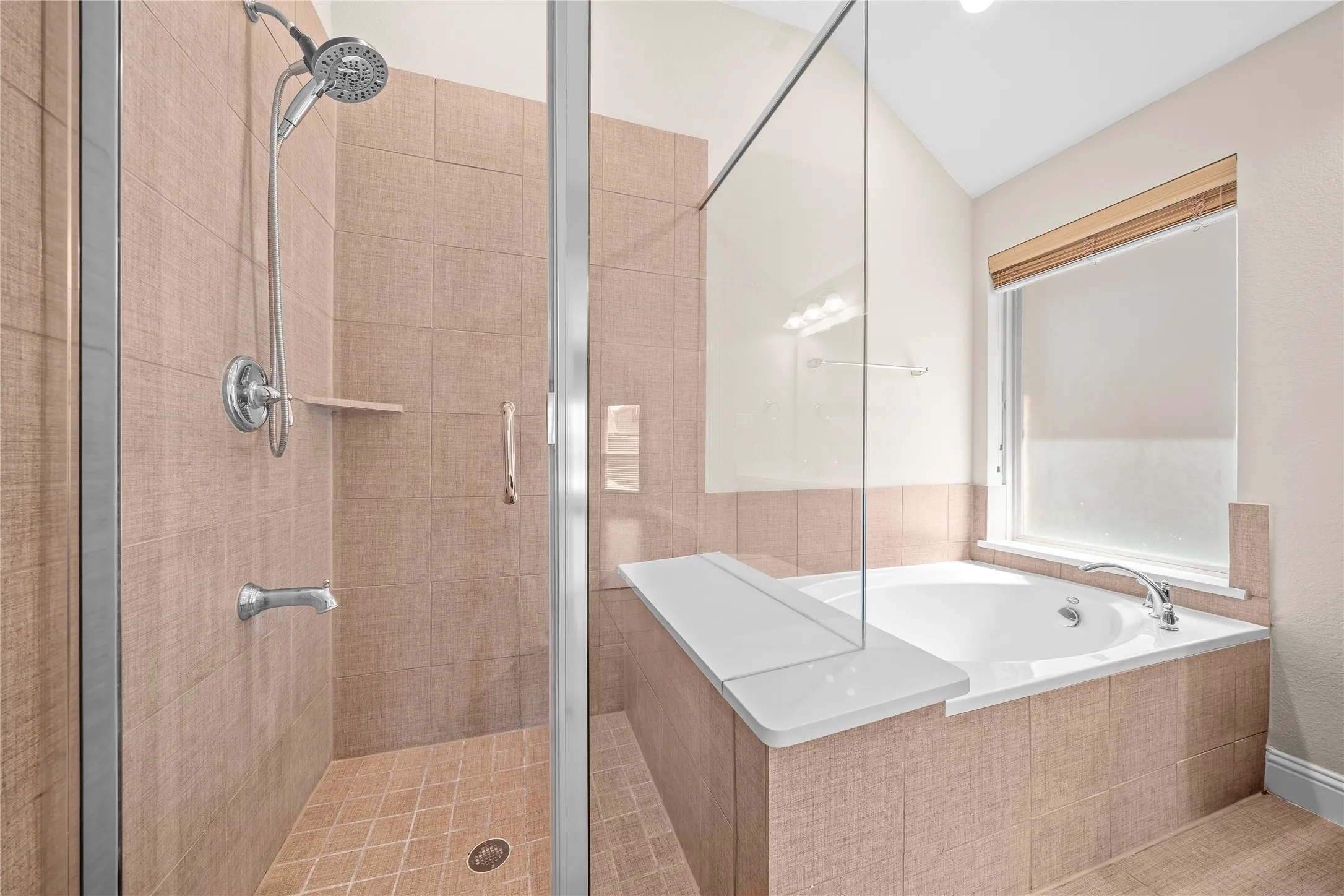 Walk-in shower with glass enclosure, separate soaking tub, and tiled surrounds