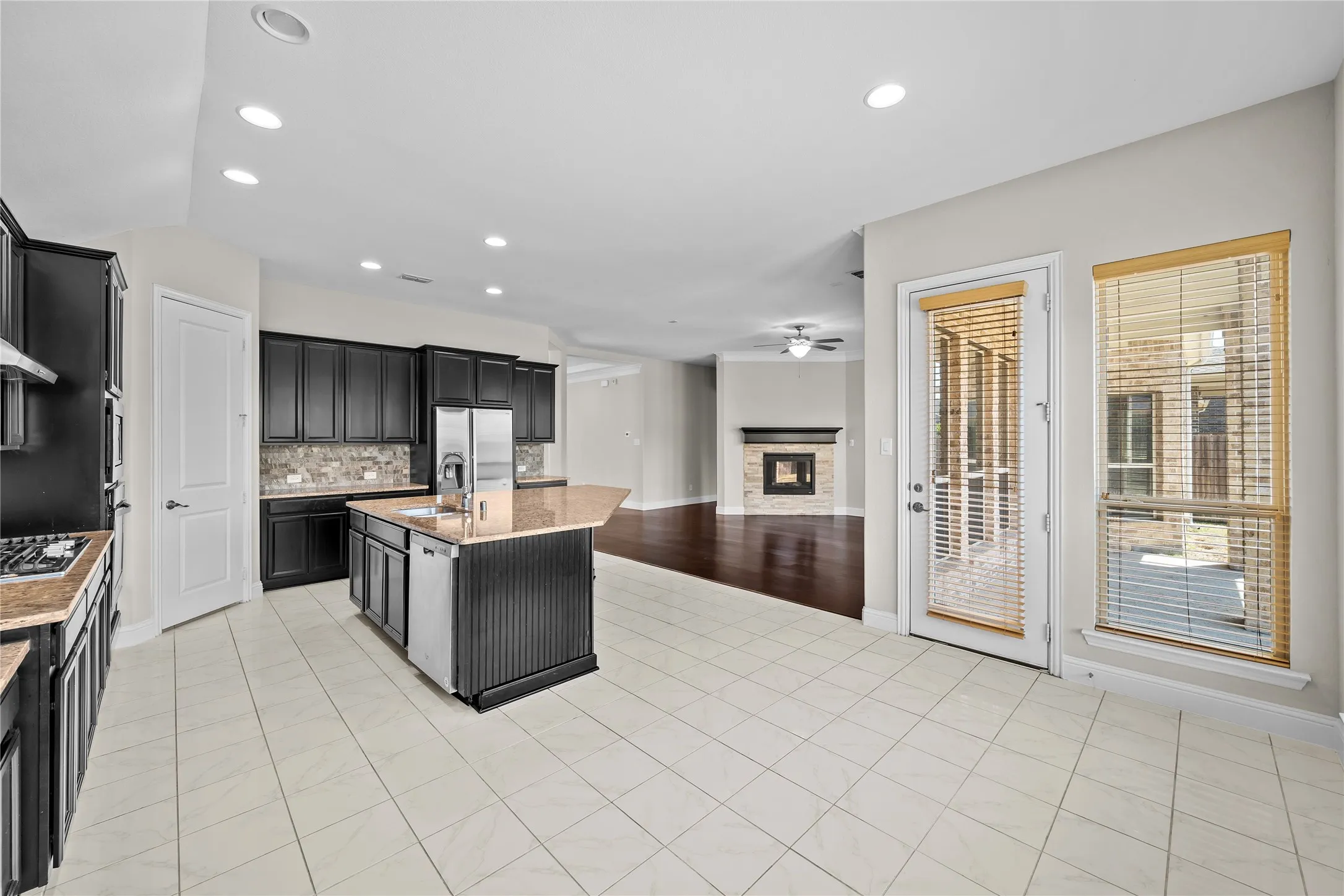 Spacious kitchen with a central island, dark wood cabinetry, and light-toned tile flooring
