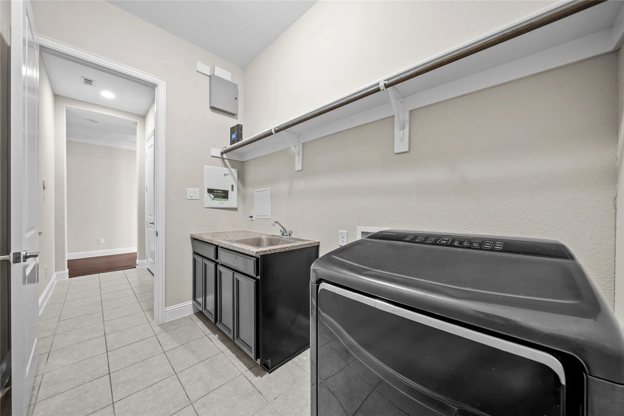 Utility space featuring a single basin sink with cabinetry, overhead shelving, and tile flooring