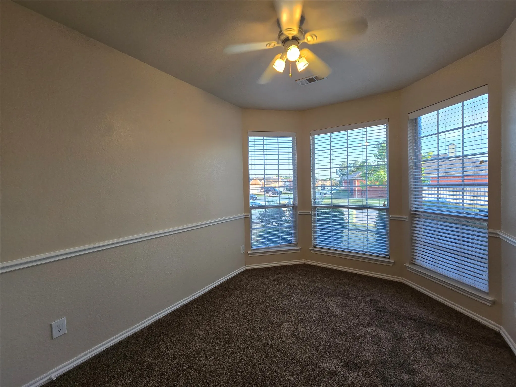 Spare room featuring dark colored carpet and ceiling fan