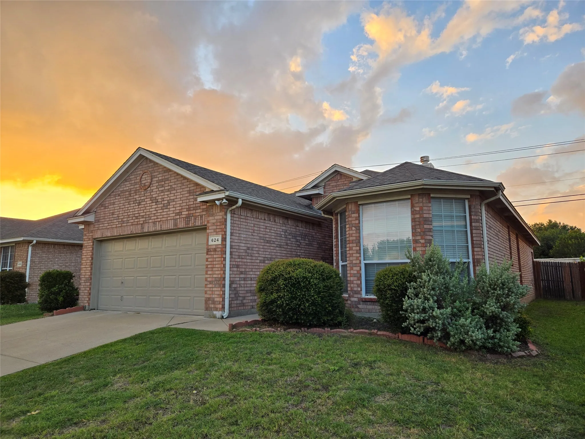 Ranch-style house featuring an attached garage, concrete driveway, brick siding, and a shingled roof