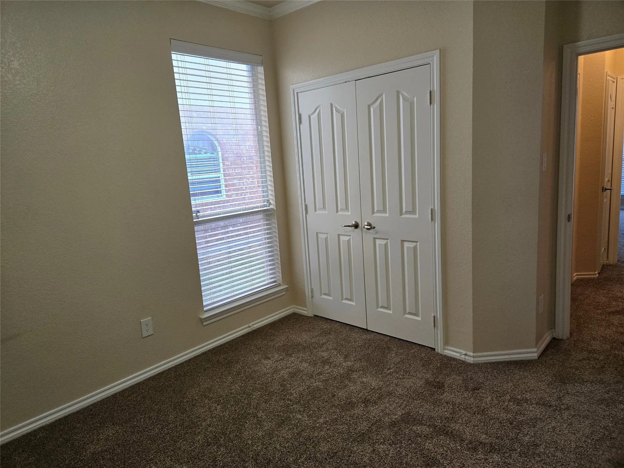 Unfurnished bedroom with dark carpet, a closet, ornamental molding, and a textured wall