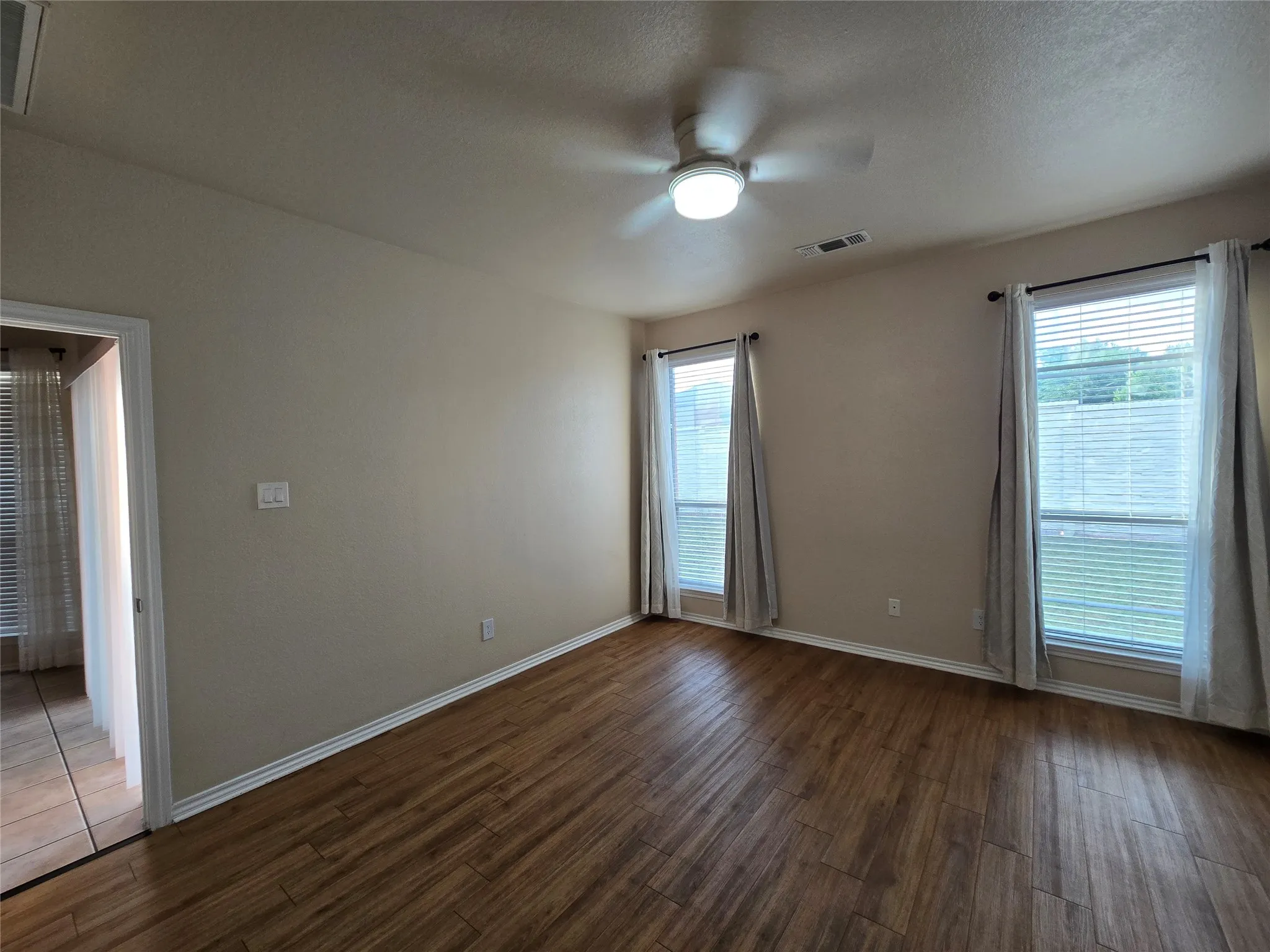 Unfurnished room with dark wood-style floors, a ceiling fan, and a textured ceiling