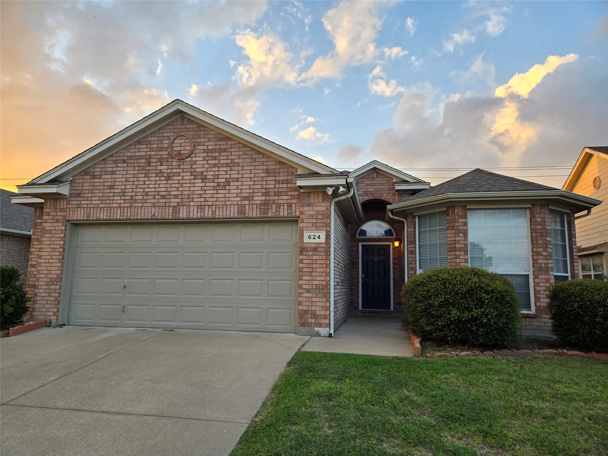 Single story home featuring a garage, driveway, brick siding, and a front lawn