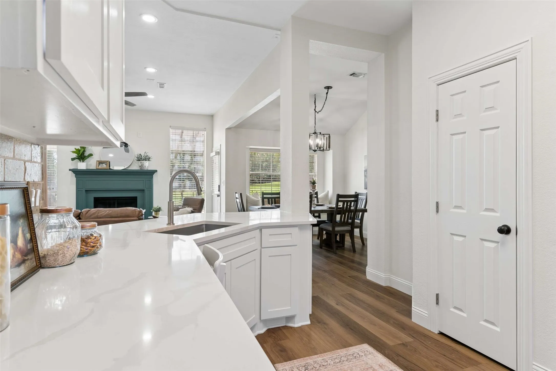 Kitchen featuring white cabinetry, light-toned countertops, a stainless steel sink, and a high-arch faucet