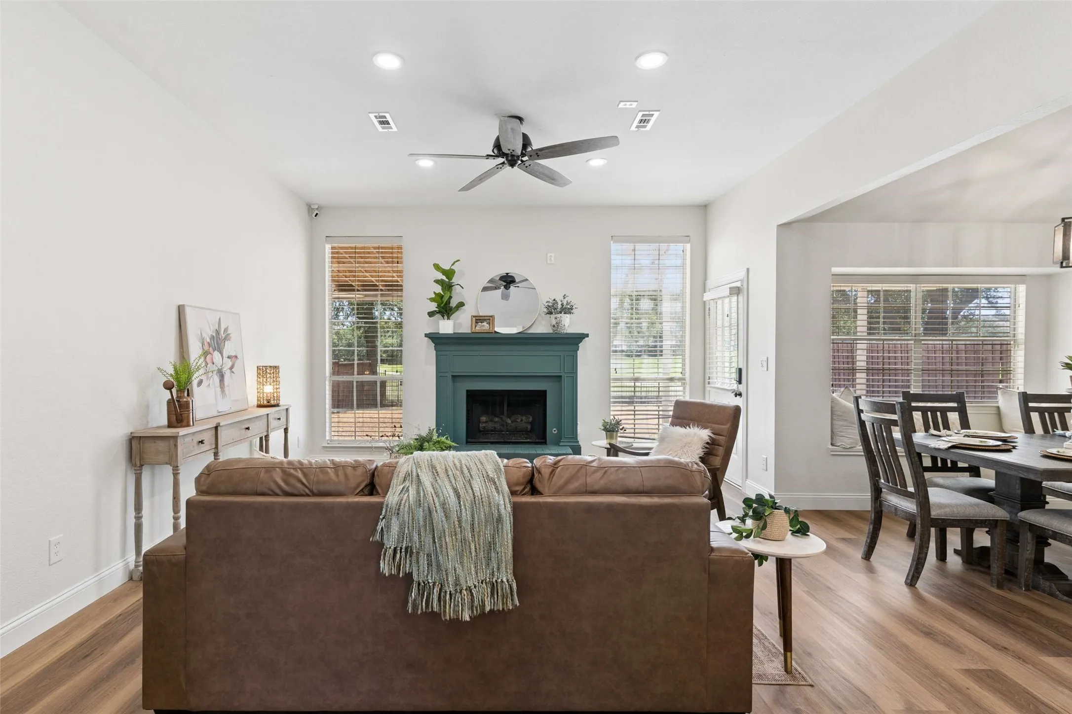Open-concept living area with wood-finish flooring, a contemporary fireplace, recessed lighting, and a ceiling fan