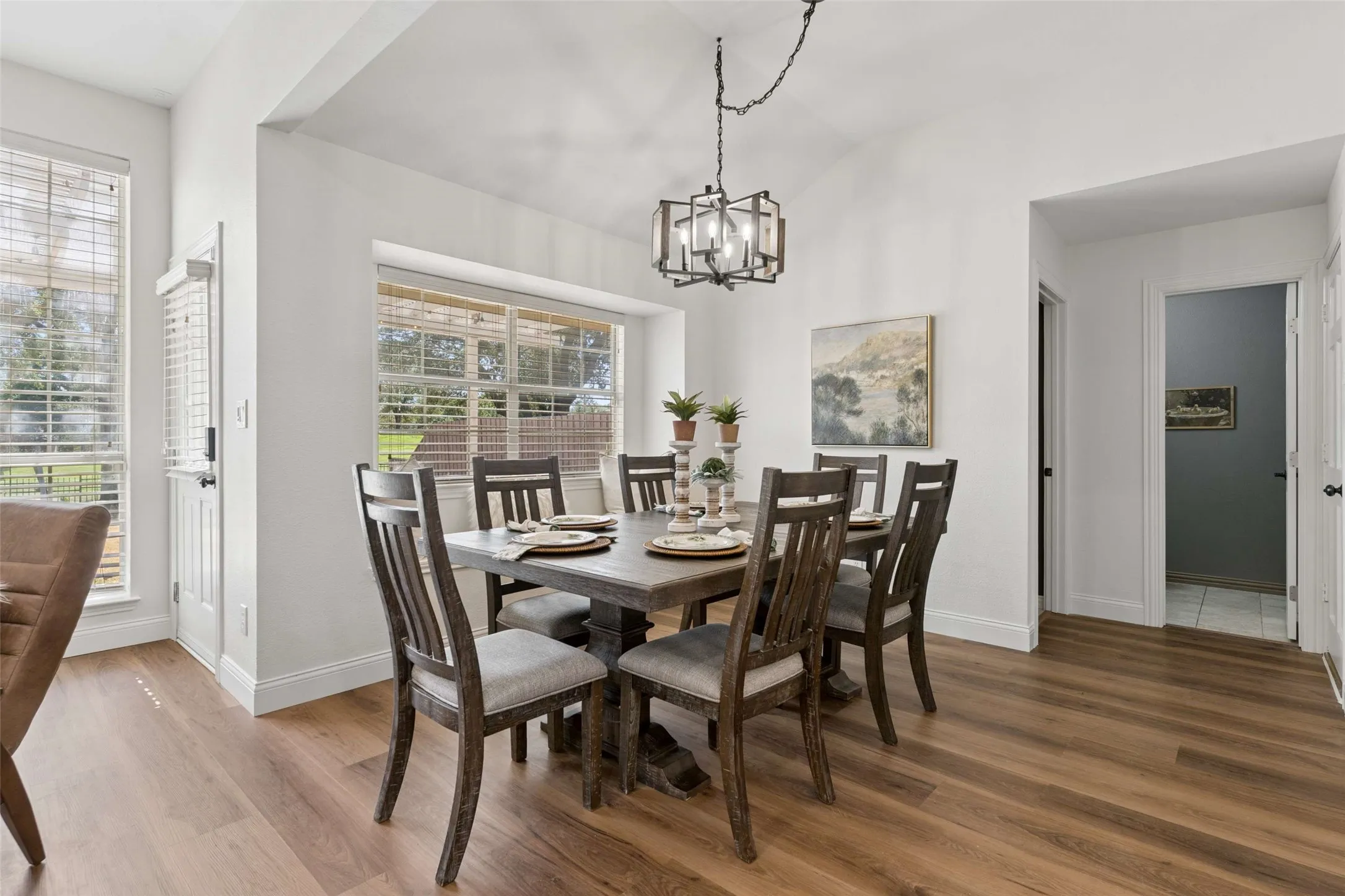 Recessed dining area with a tray ceiling and wood-finish flooring