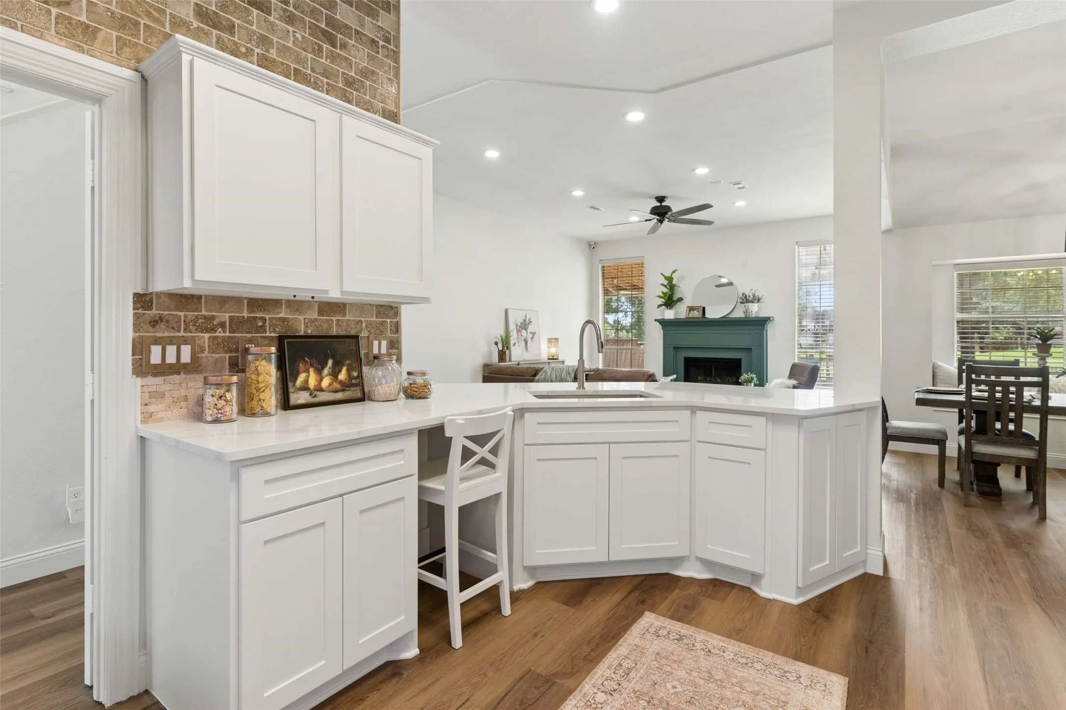 White shaker cabinetry with stone countertops, a subway tile backsplash, and wood-finish flooring