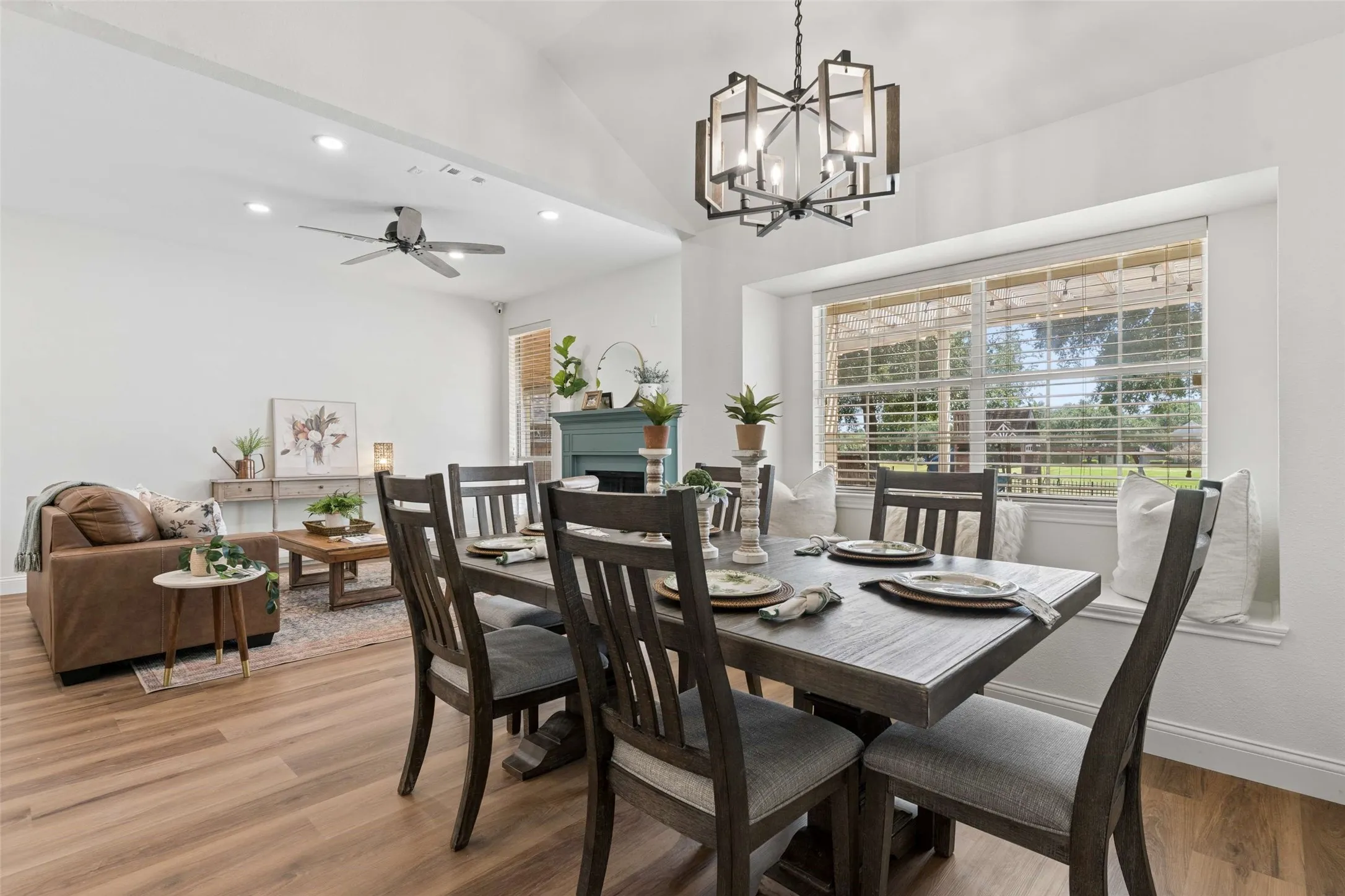 Vaulted ceiling with a contemporary chandelier, wood-finish flooring, recessed lighting, and a window seat with a large picture window