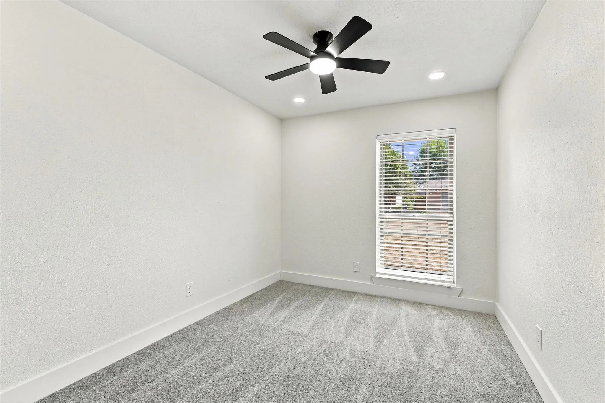 Soft gray carpeting, white walls, and a window with horizontal blinds
