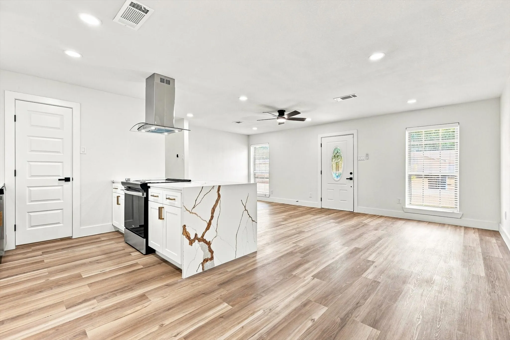 Open-concept living area with wood-finish flooring, recessed lighting, and a ceiling fan