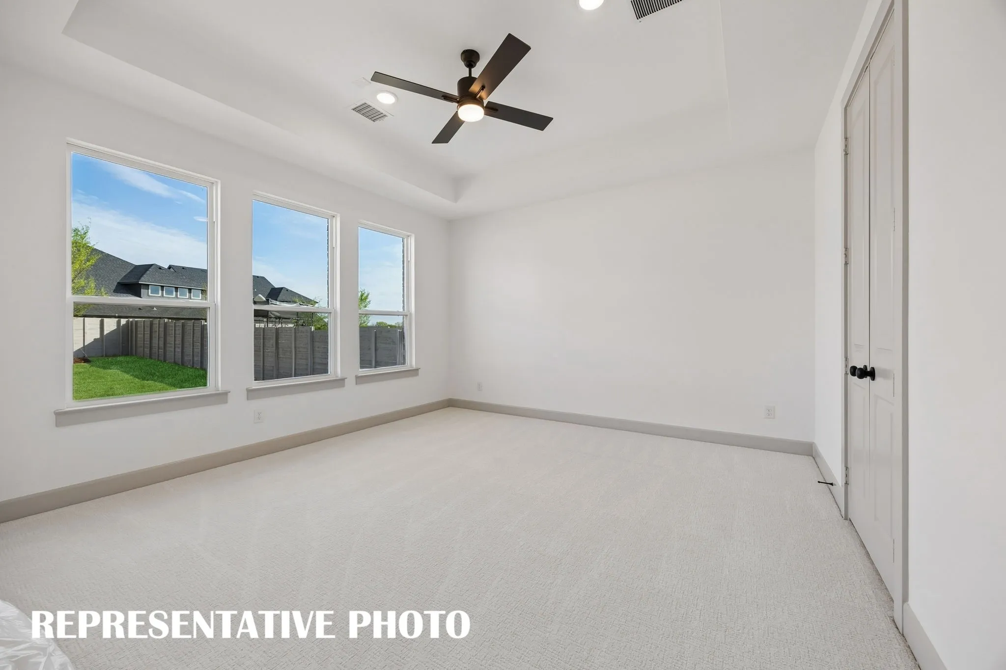 Featuring a wall of windows, high ceilings and plush carpeting, this dreamy owner's suite is the perfect place to relax and unwind at the end of the day.  REPRESENTATIVE PHOTO