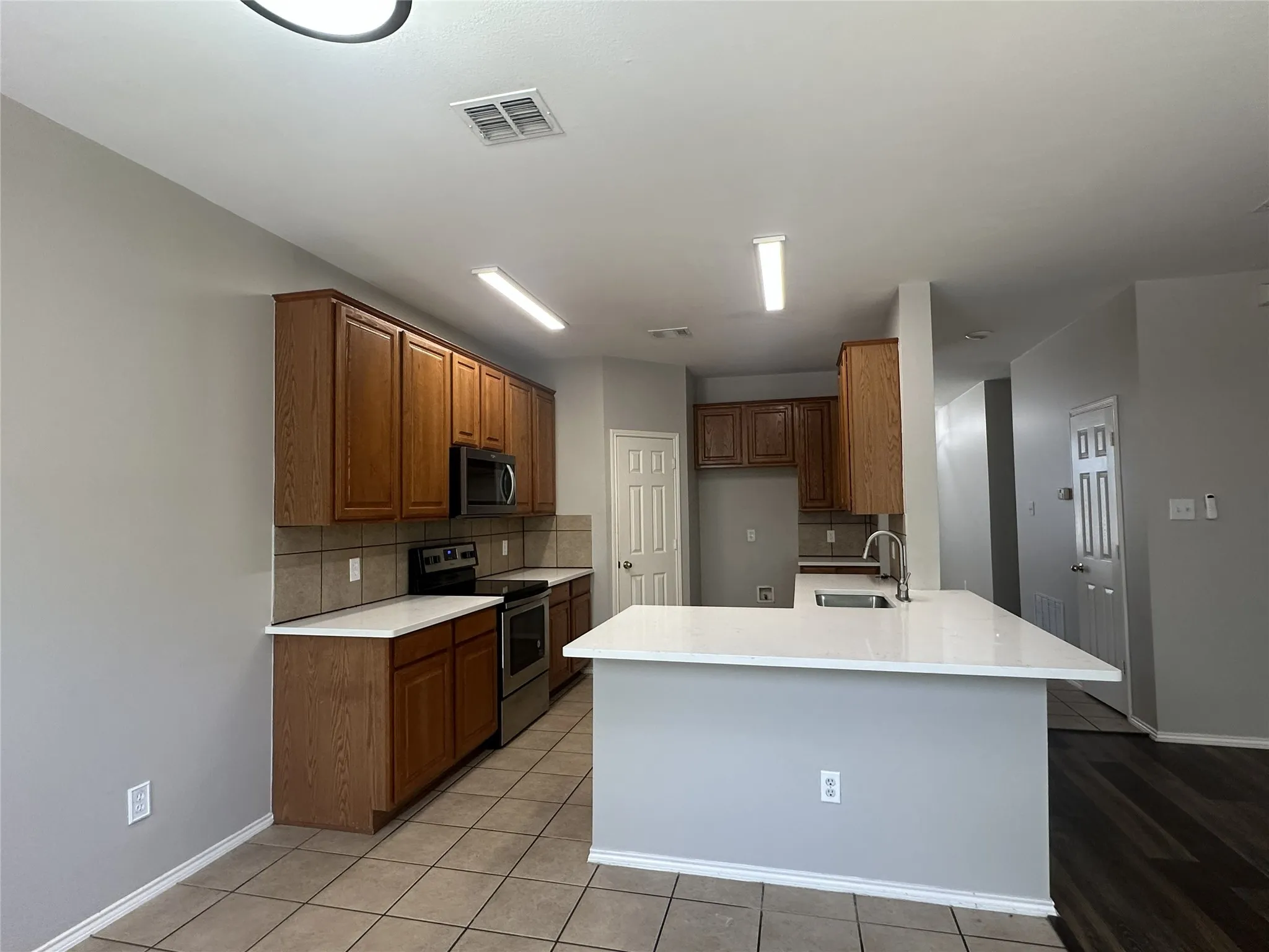 Kitchen featuring wood cabinetry, white countertops, tile backsplash, and stainless steel appliances