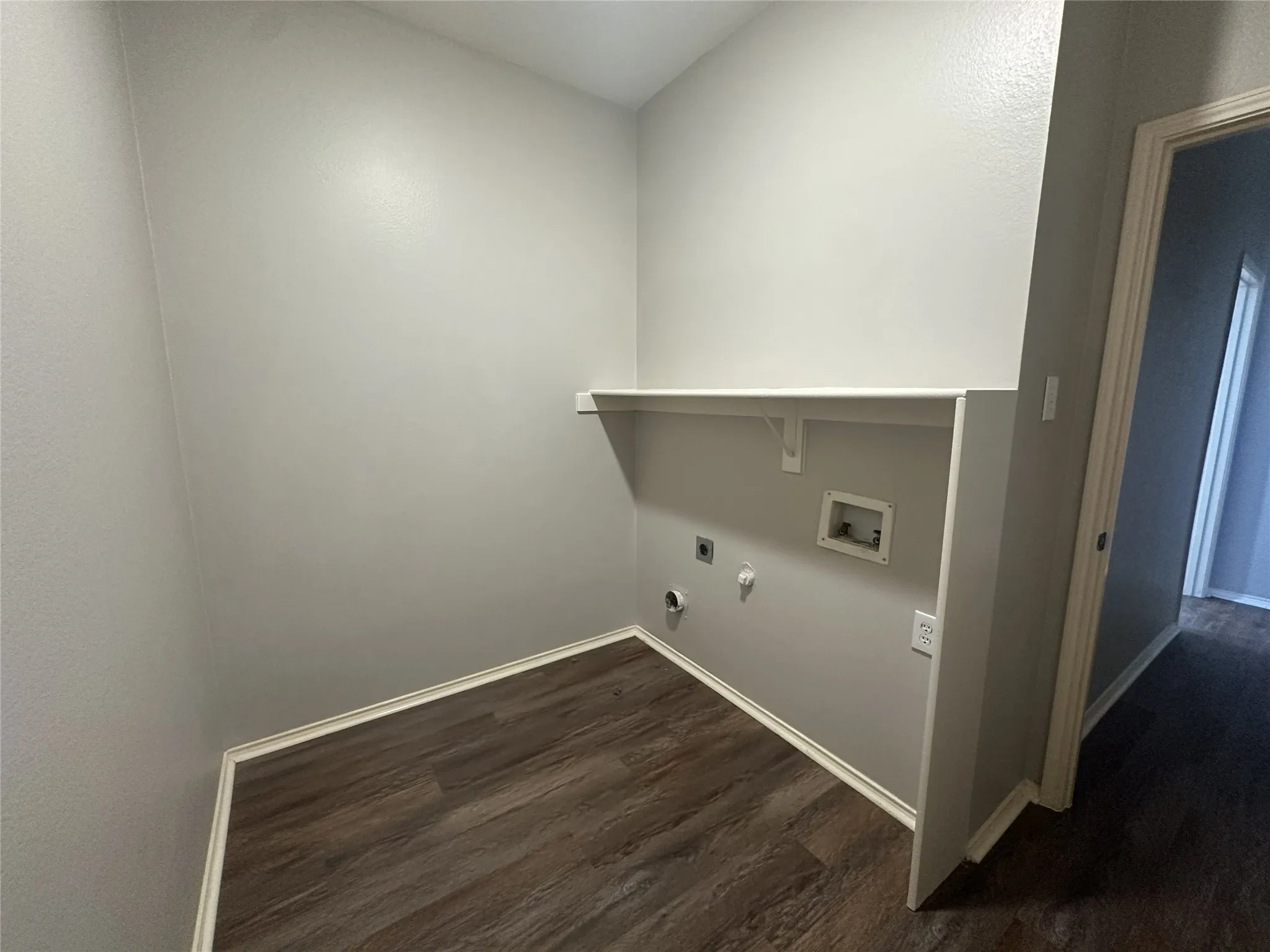 Utility space featuring wood-finish flooring, a built-in shelf, and appliance hookups