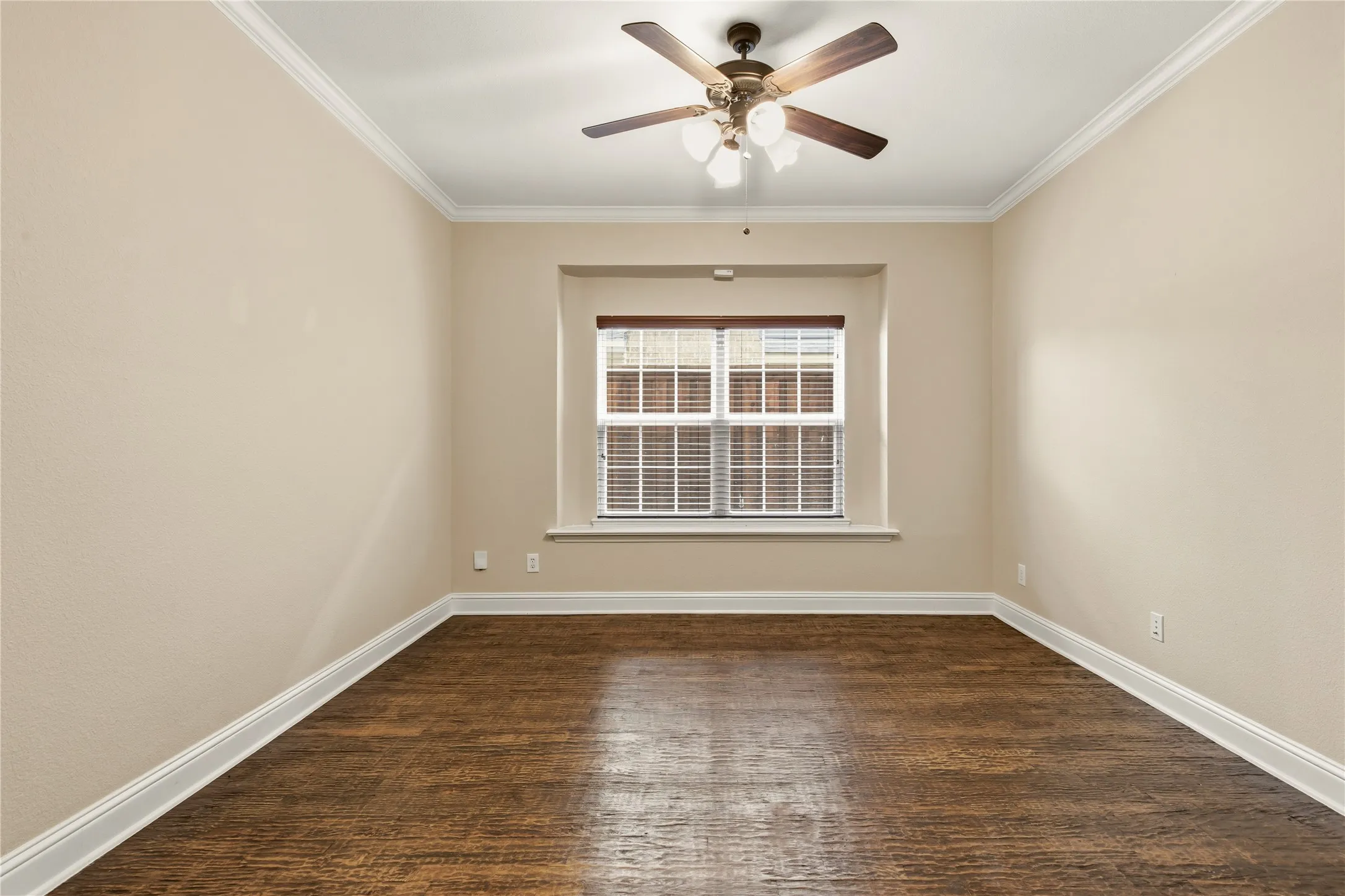 Room featuring wood-finish flooring, neutral wall tones, crown molding, and a ceiling fan with light kit