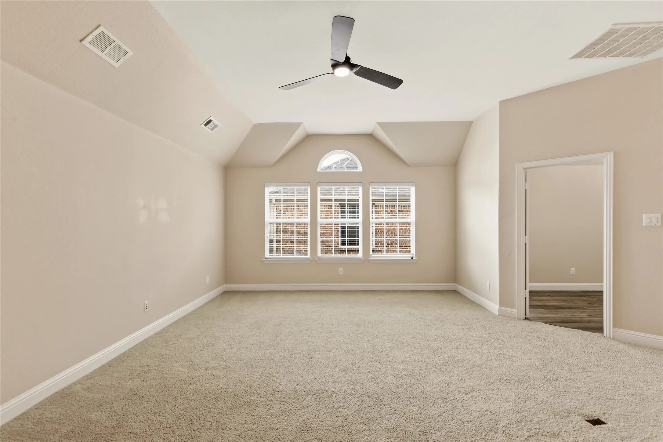 Carpeted interior space featuring a vaulted ceiling and a modern ceiling fan