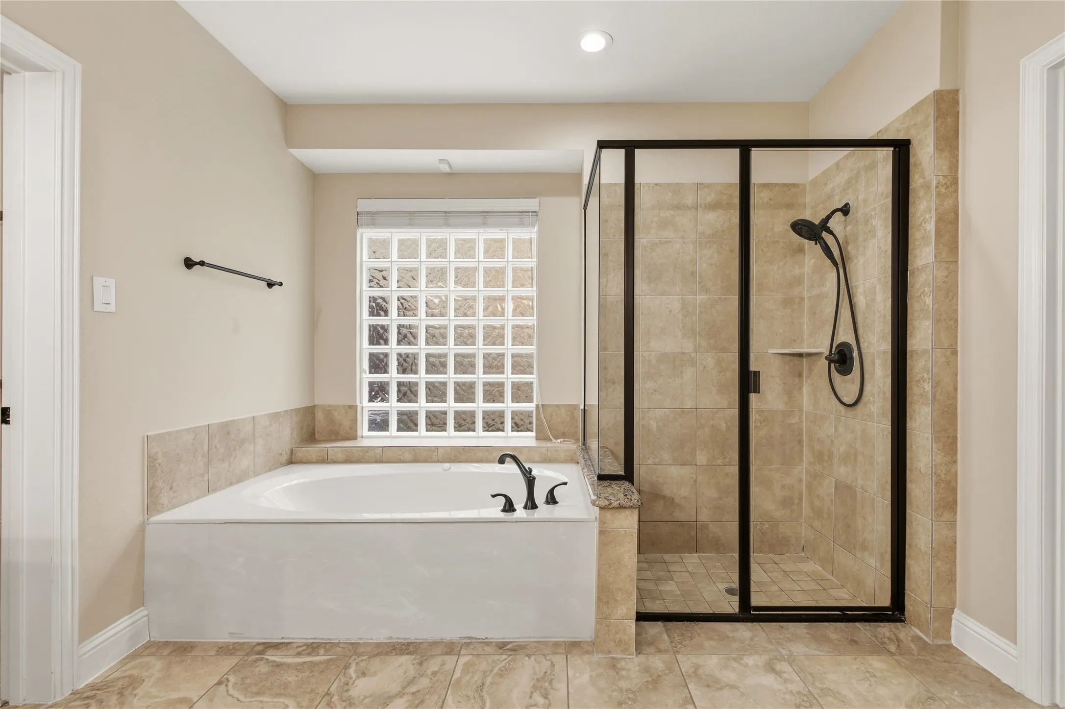 Enclosed shower with matte black fixtures, an integral shelf, and a glass door with dark trim