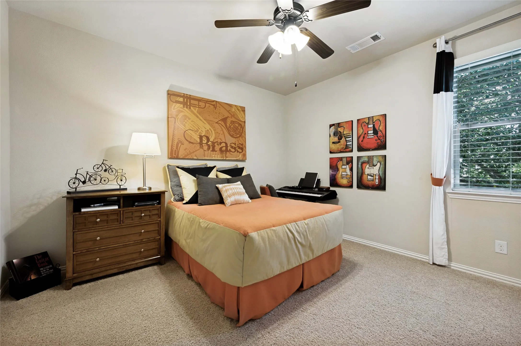 This secondary bedroom is spacious and located on the upper level, featuring a ceiling fan with integrated lighting, a walk-in closet, and scenic views of the surrounding trees.