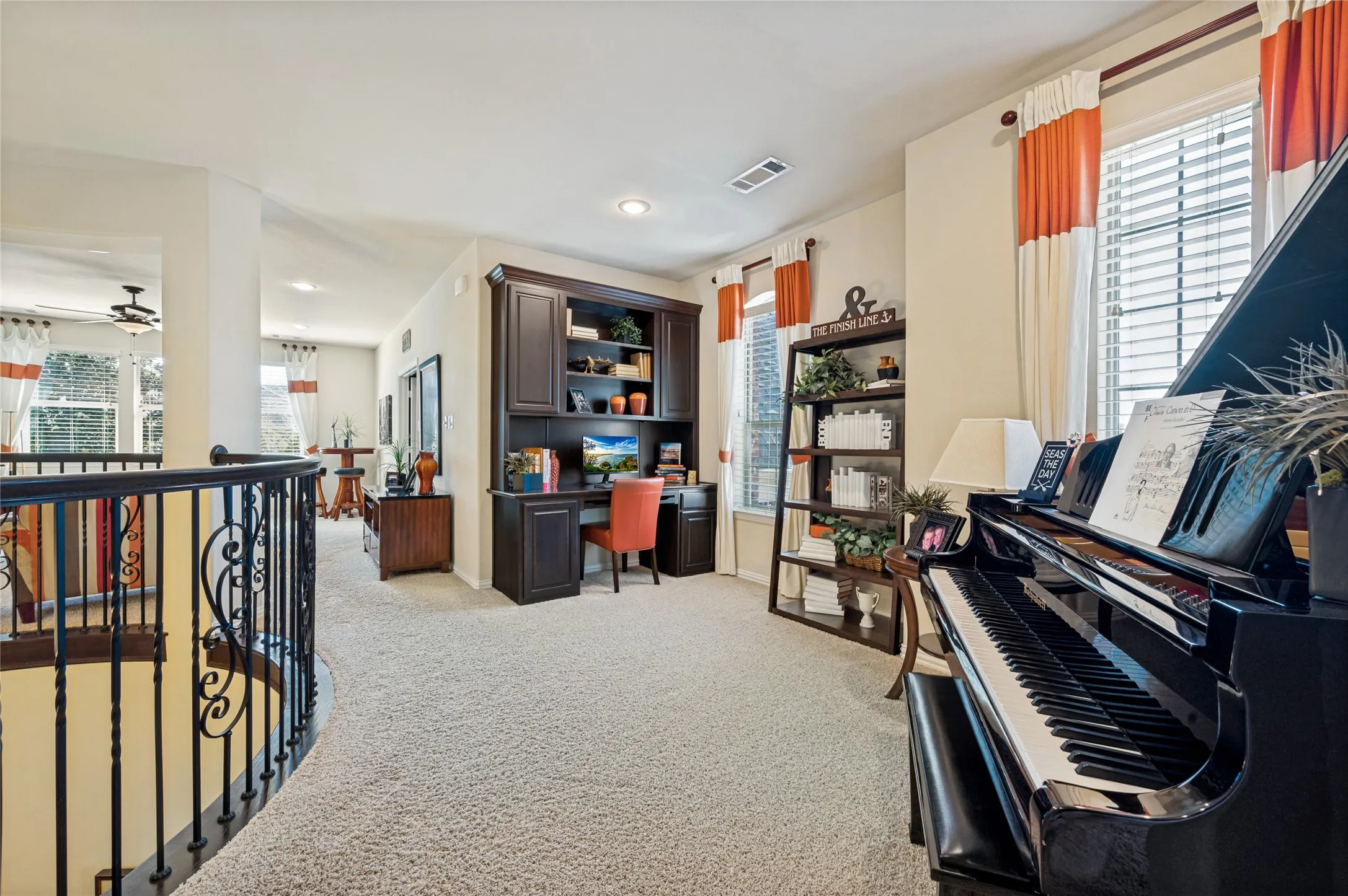 The upstairs area features a spacious built-in desk complemented by custom cabinetry, integrated shelving, and elegant recessed lighting.