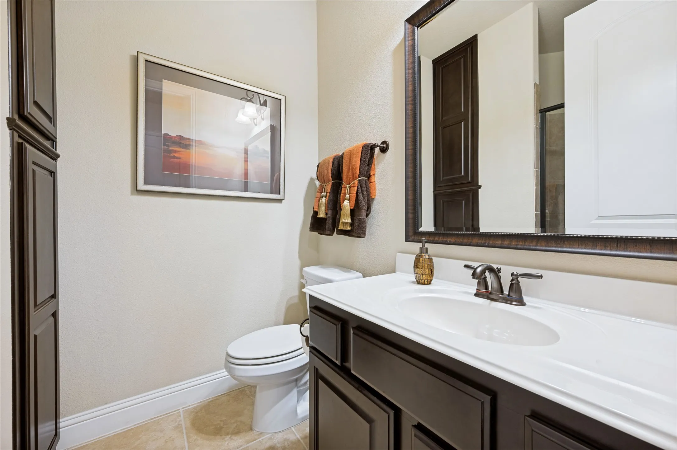 This guest suite bathroom features a walk-in shower, ample storage cabinetry, bronze-finish fixtures, a framed mirror, and tile flooring.