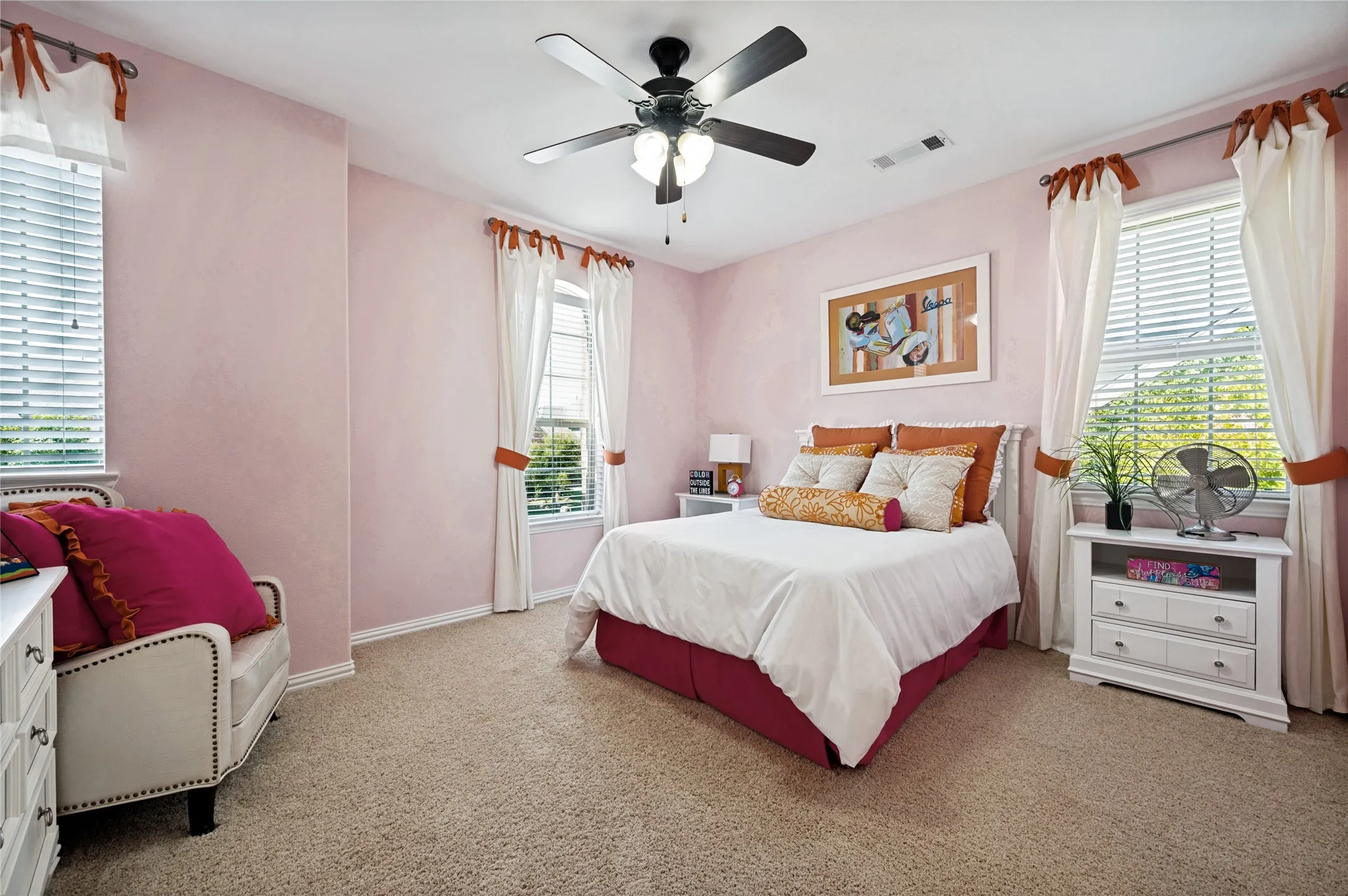 This upstairs secondary bedroom features a ceiling fan, a walk-in closet, abundant natural light from multiple windows, and direct access to a Jack and Jill bathroom.
