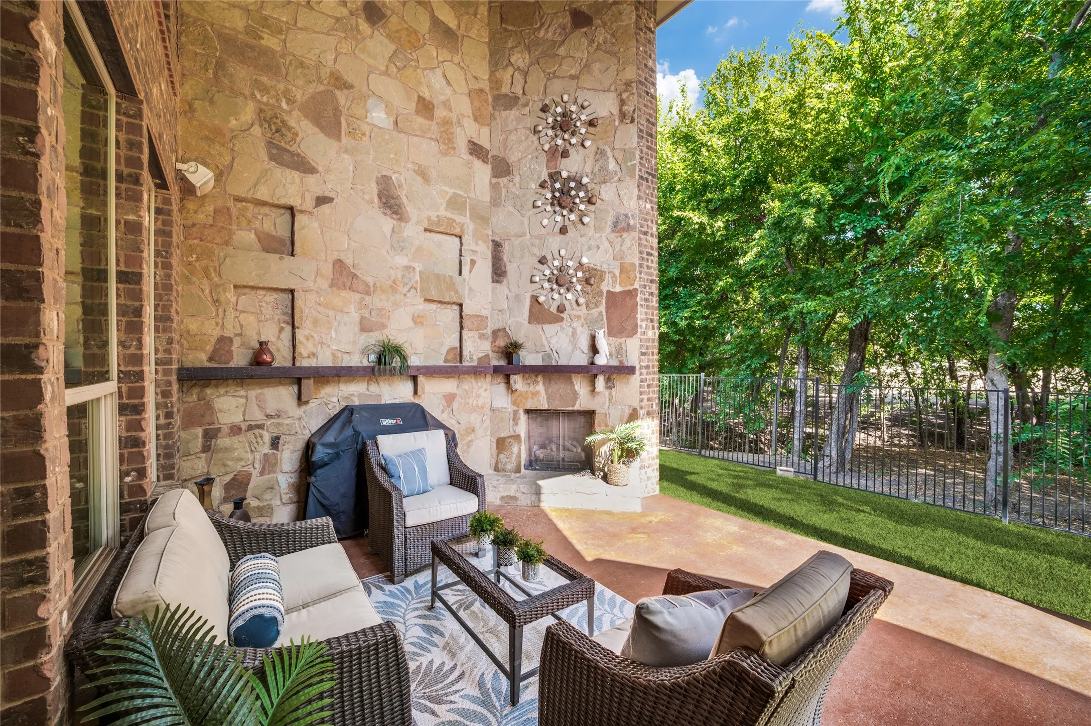 Enjoy this exquisite outdoor living space, which features a two-story covered patio, a stone-clad wall, and an integrated fireplace with scenic views of the trees.