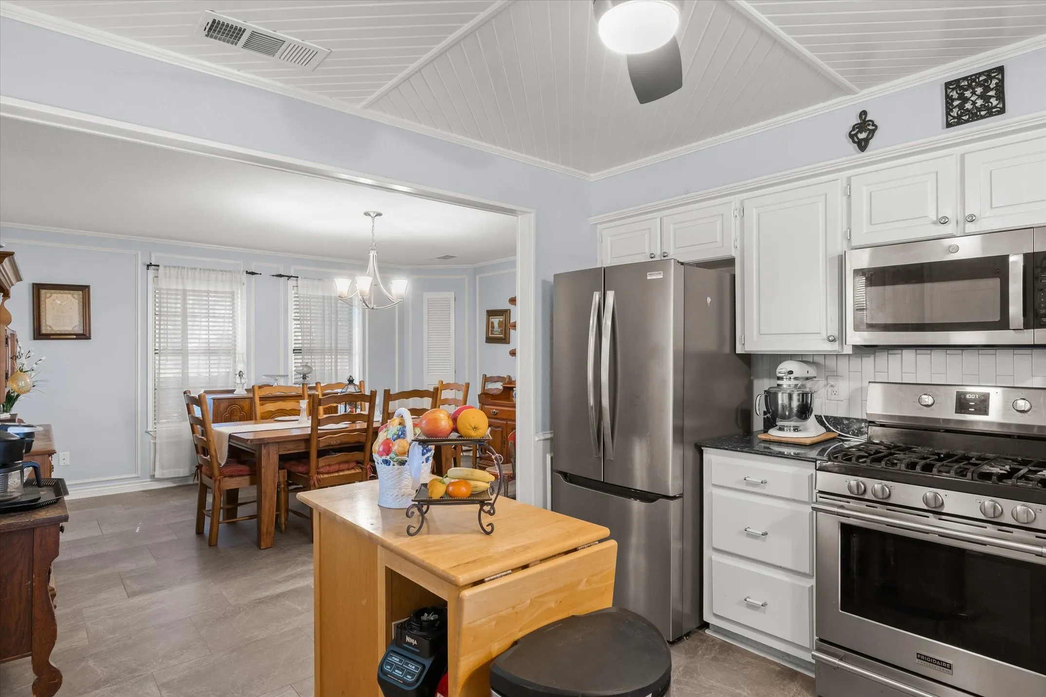 Kitchen featuring stainless steel appliances, white cabinetry, dark countertops, and a subway tile backsplash