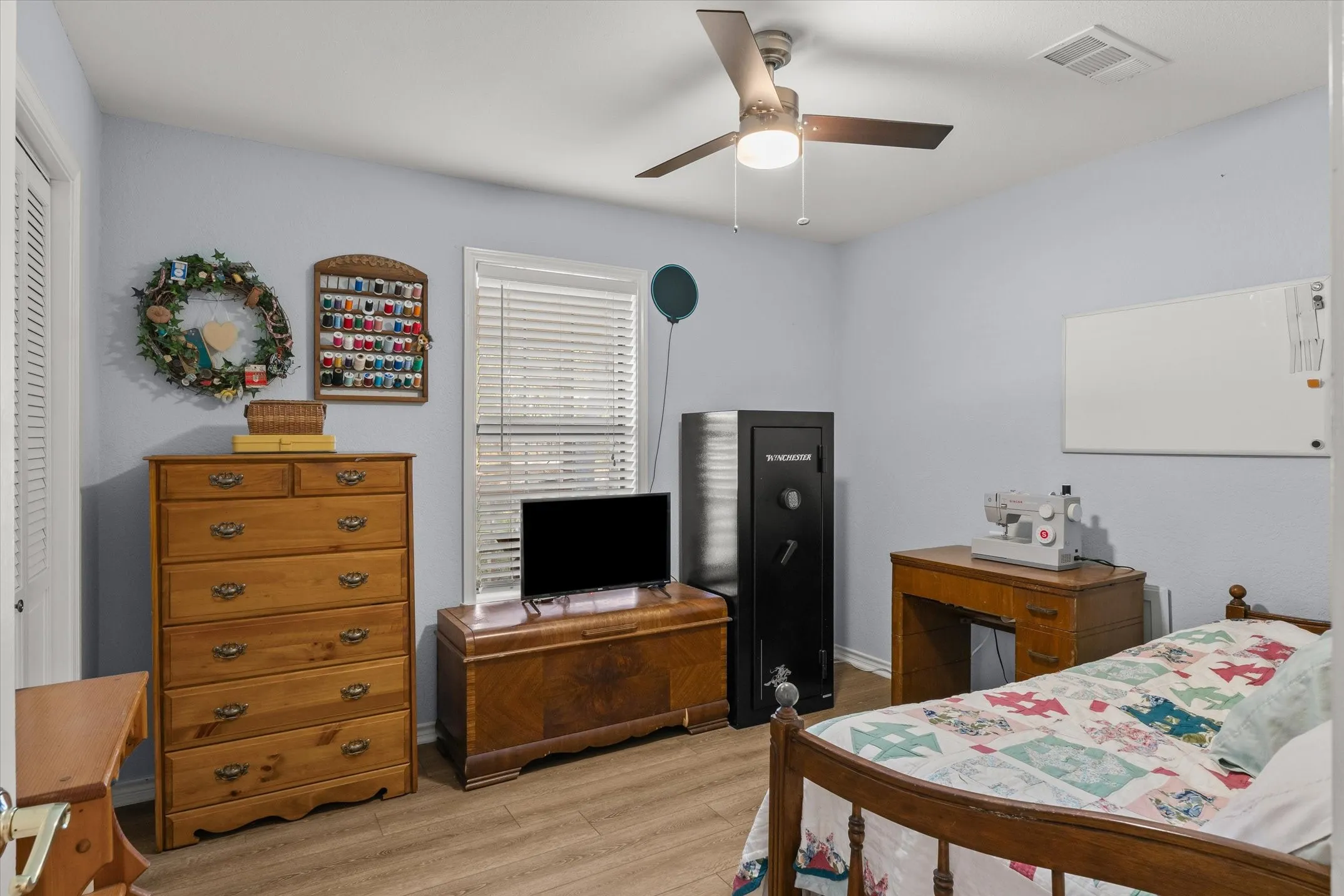 Wood-finish flooring, ceiling fan with integrated lighting, white window blinds, and a built-in closet with louvered doors