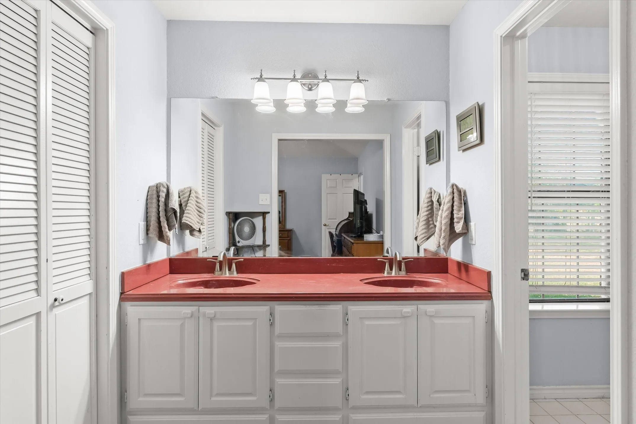 Dual vanity with individual sinks, white cabinetry, and a red countertop