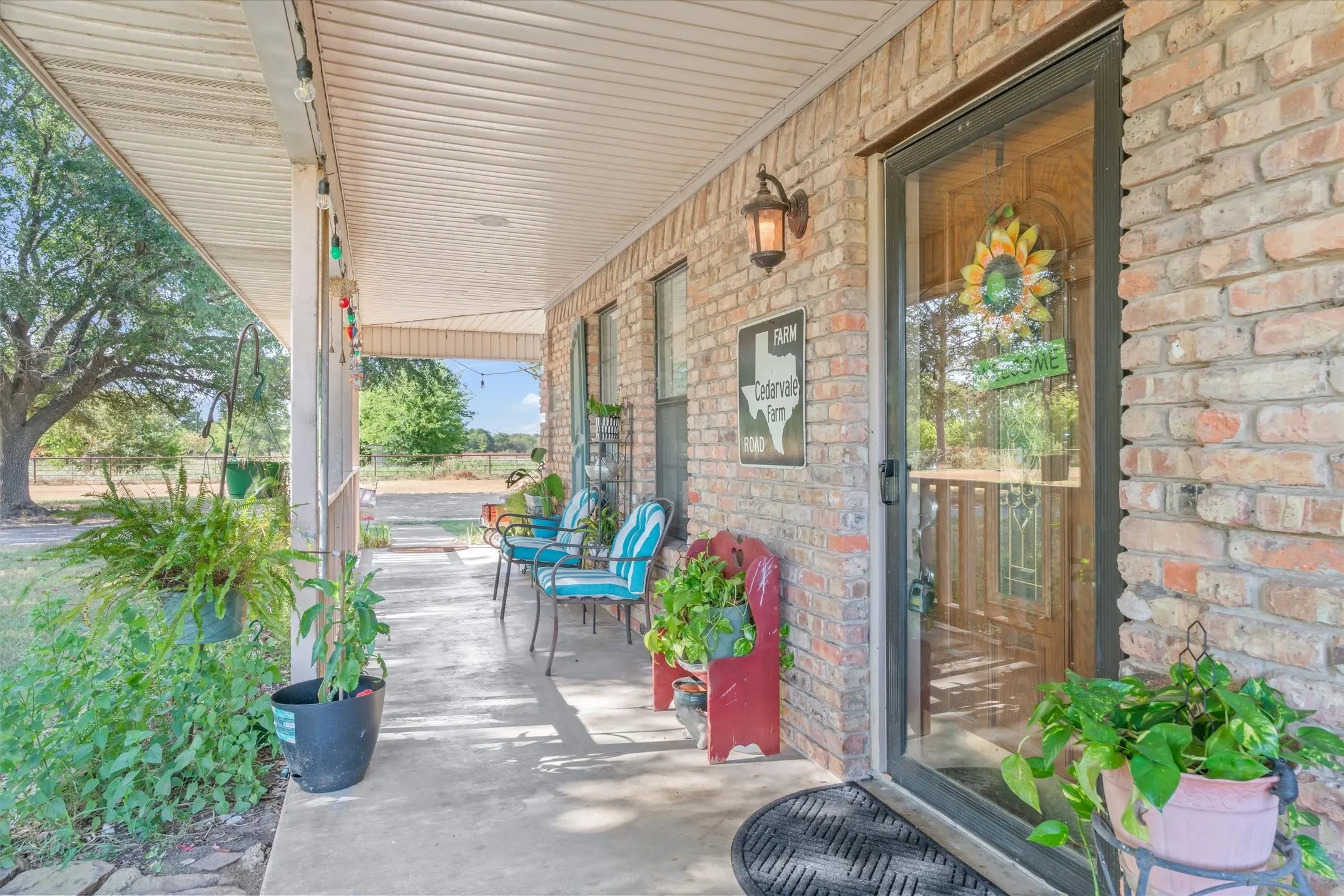 Brick exterior, covered porch, concrete flooring, exterior wall sconce, glass-paneled entry door