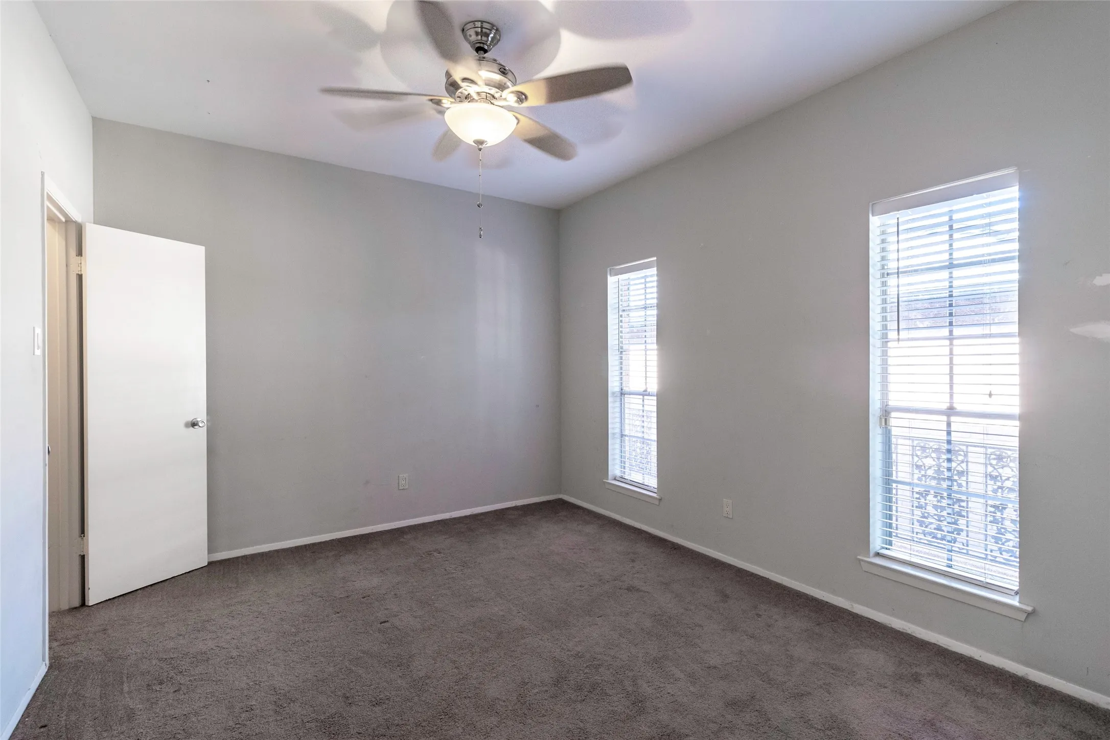 Carpeted room featuring ceiling fan and baseboards
