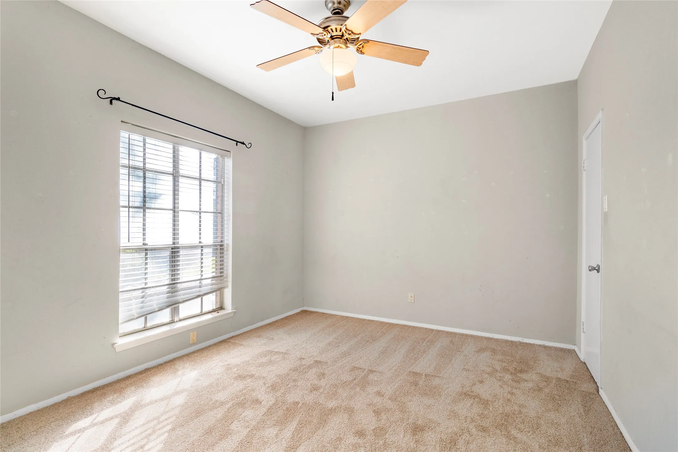 Spare room with light carpet and a ceiling fan