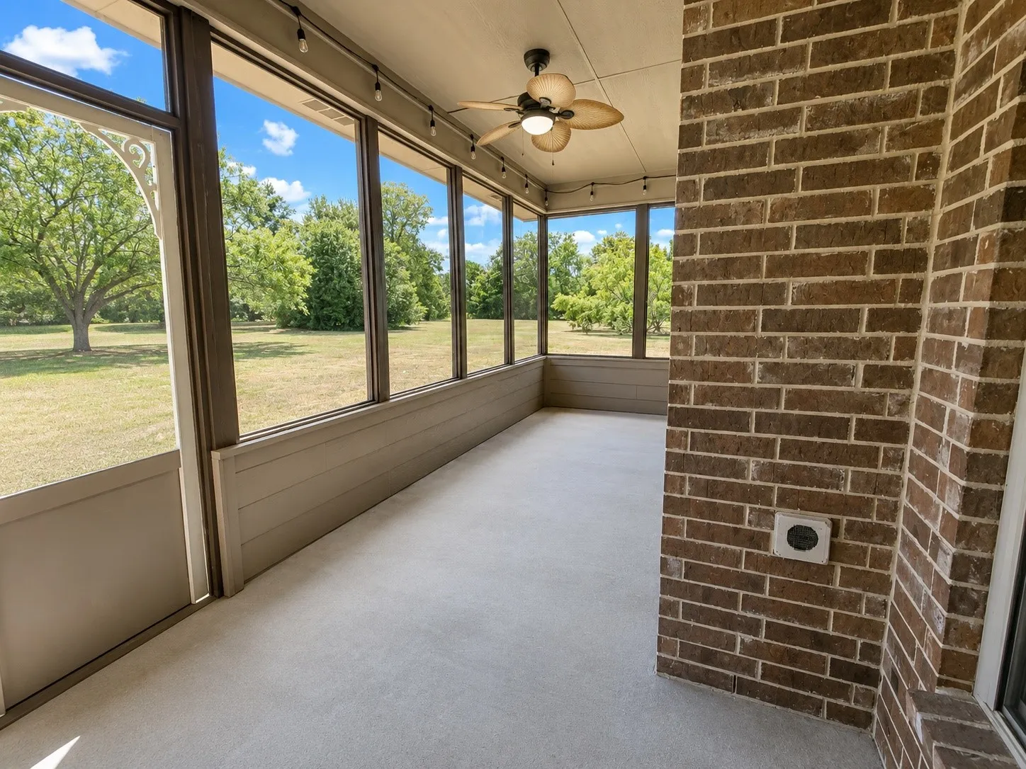 Screened porch with brick wall, ceiling fan, track lighting, and expansive outdoor scenery