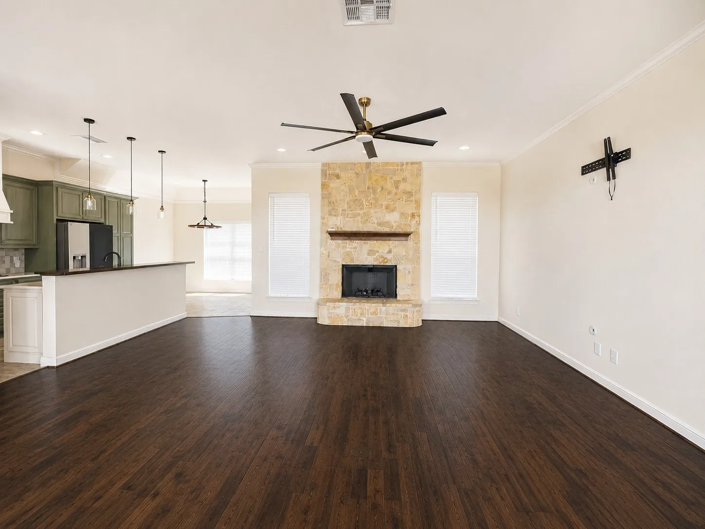Wood-finish flooring throughout, stone-clad fireplace, kitchen island with breakfast bar, recessed lighting, and ceiling fan