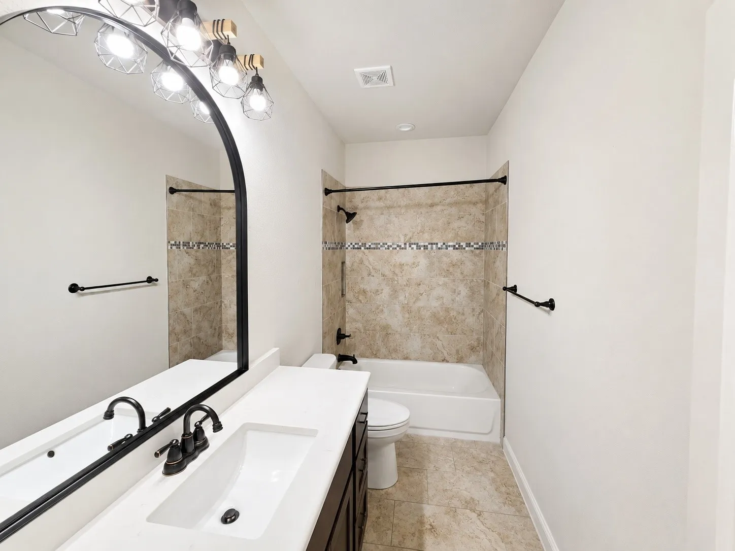 White countertop vanity with integrated sink, dark wood-finish cabinetry, and black hardware