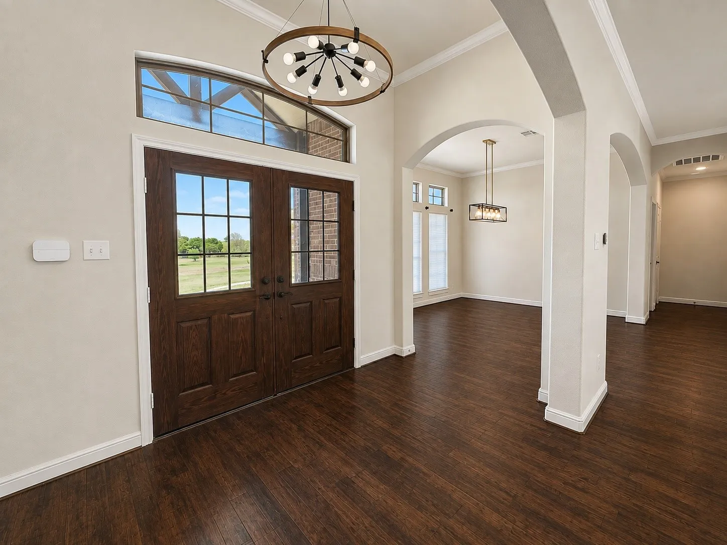 Double-door entry with transom window, wood-finish flooring, recessed lighting, and arched doorways